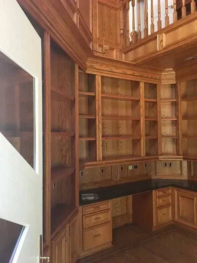 Wood-paneled built-in corner bookshelf and cabinets beneath a staircase in a home interior
