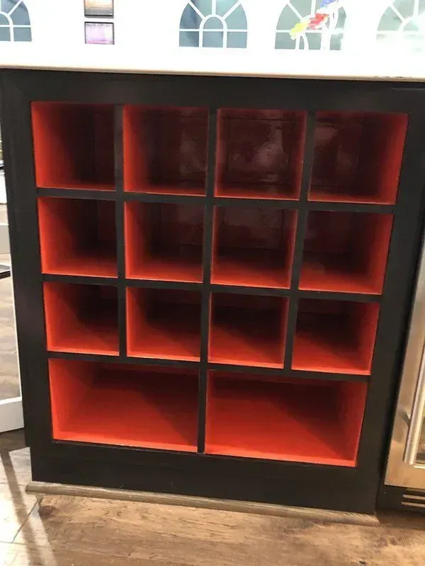 Red empty cubby shelf with eight compartments against a wall.