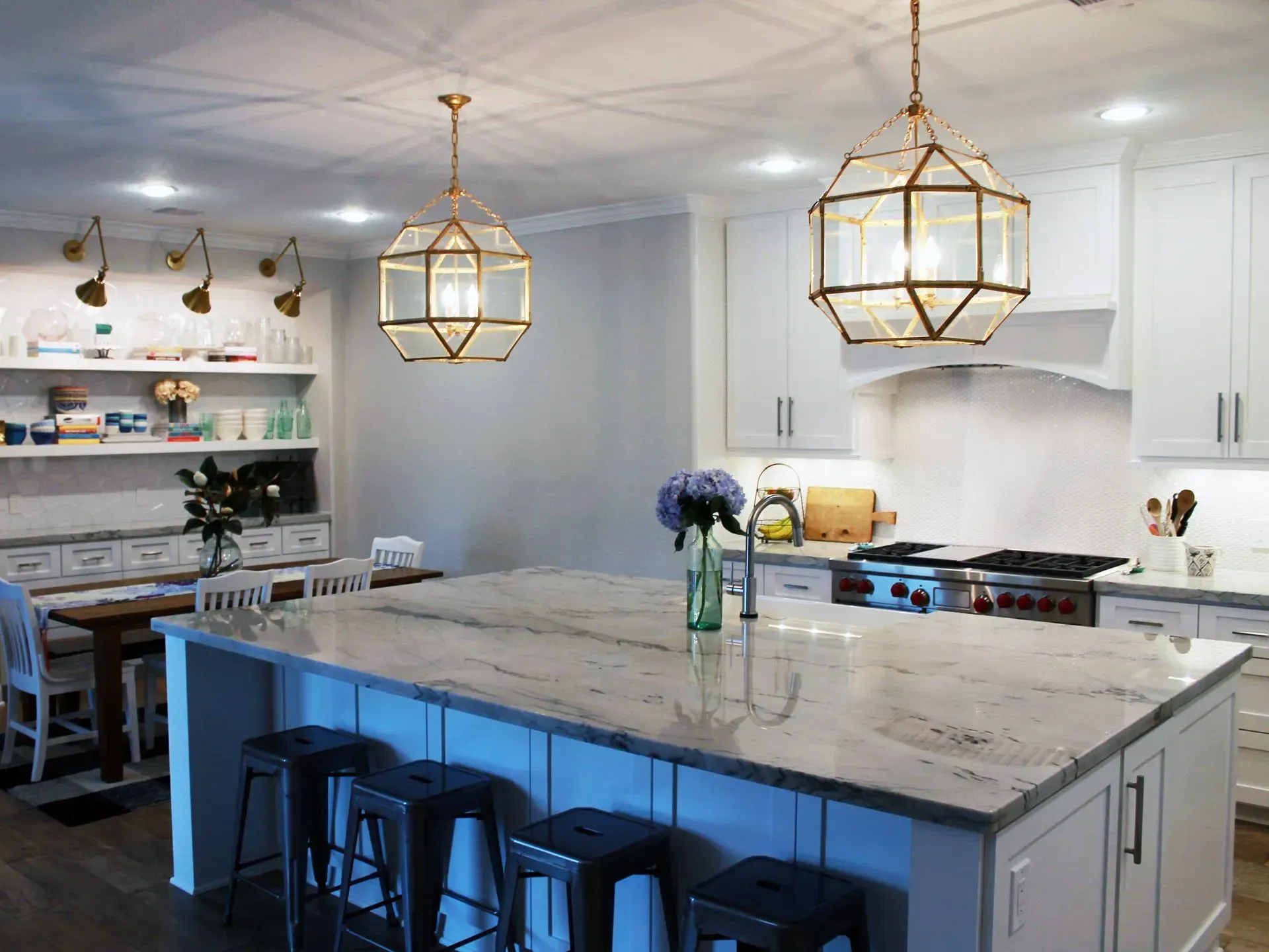 Bright modern kitchen with large marble island, pendant lights, bar stools, and white cabinets