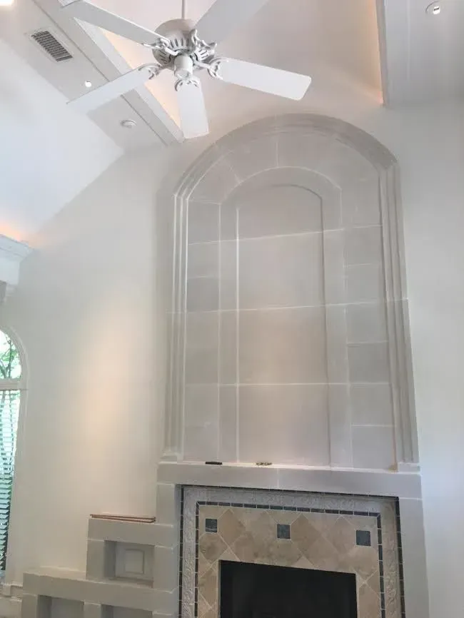 Bright living room with vaulted ceiling, white ceiling fan, and a large arched wall niche above a fireplace