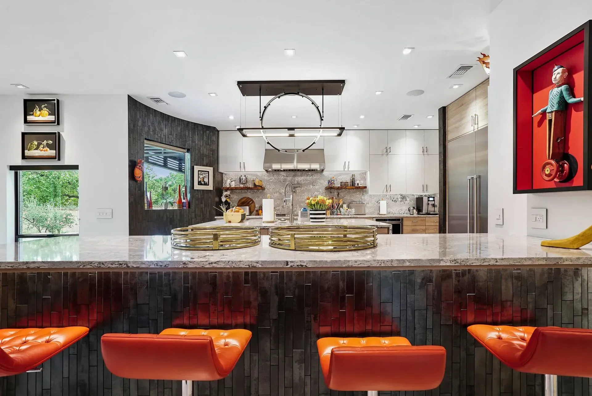 Modern kitchen with granite island, orange barstools, and white cabinetry in a bright open space