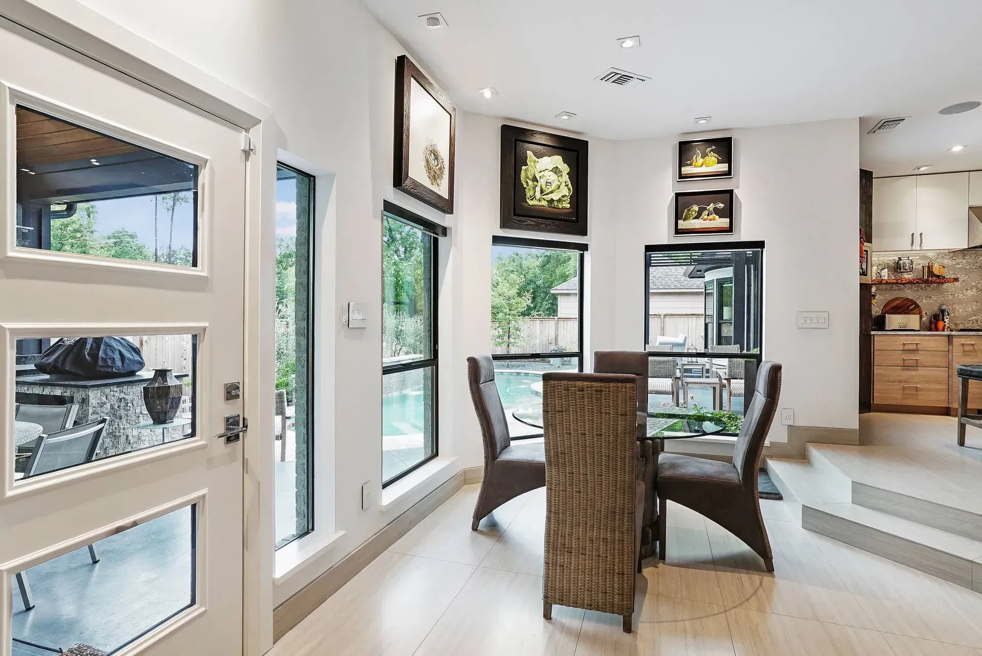 Bright dining area with wicker chairs, glass table, and large windows in a modern home