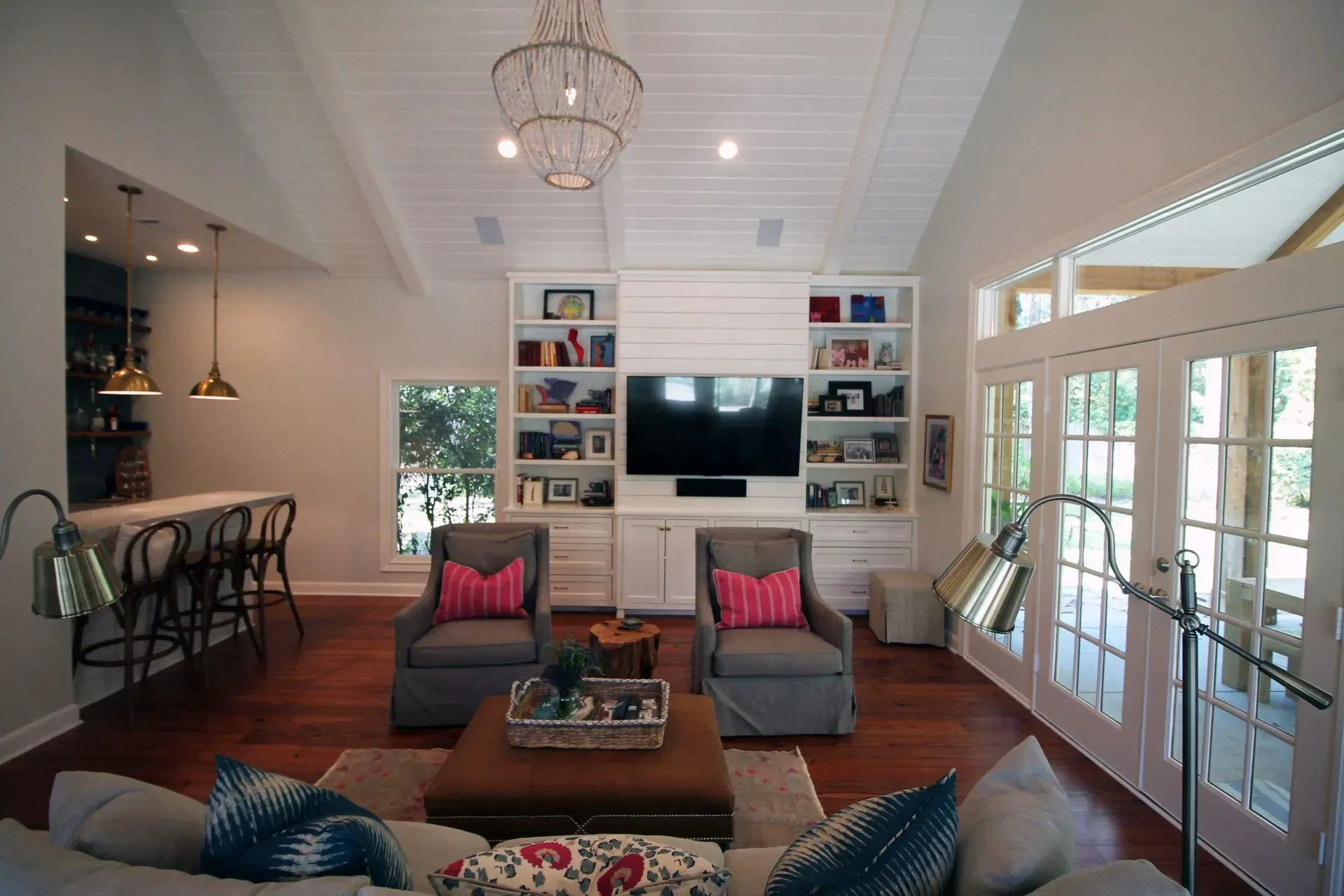 Bright living room with white built-ins, a fireplace, large windows, and modern seating around a coffee table