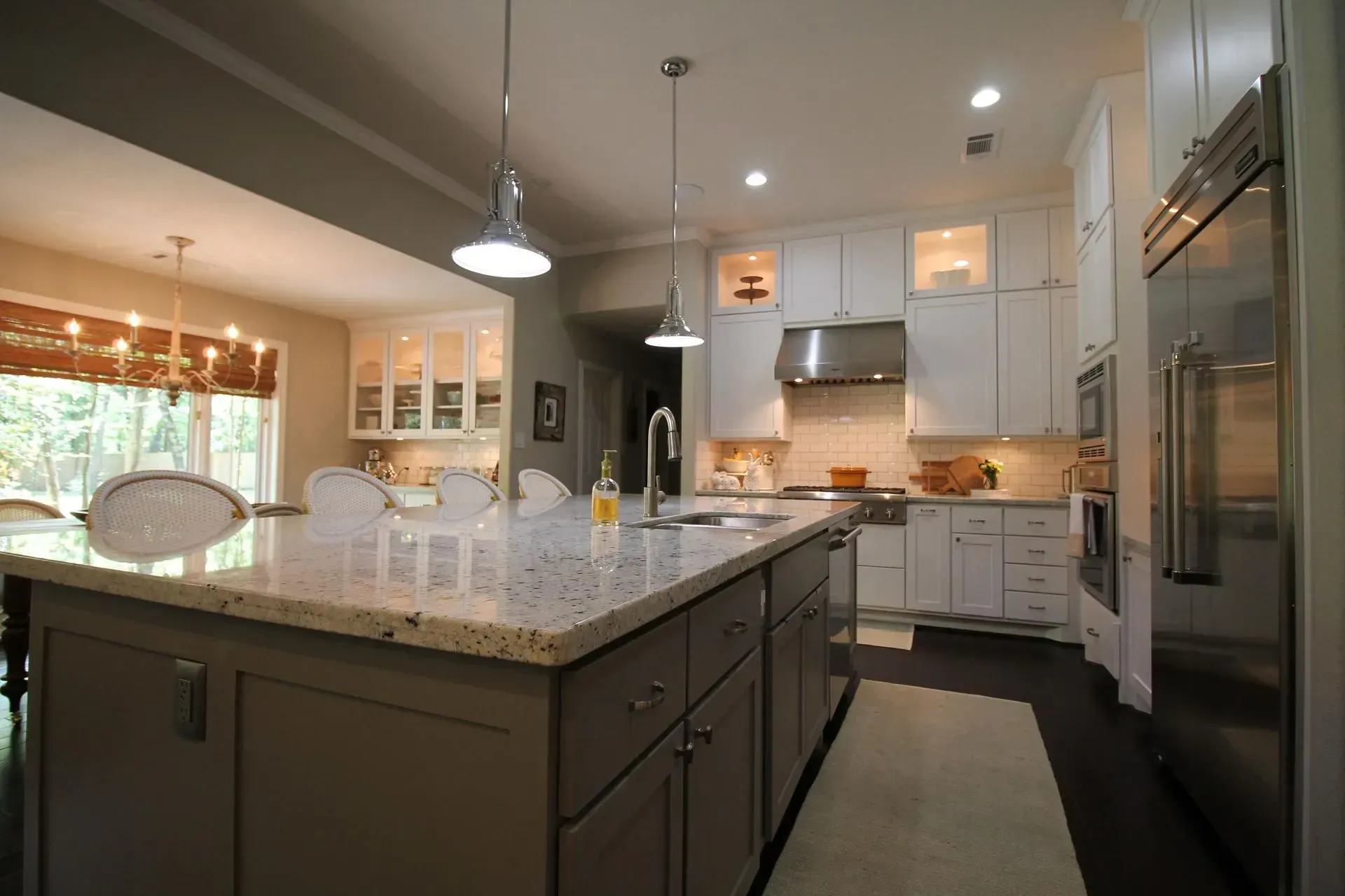 Modern kitchen with white cabinets, granite island, pendant lights, and stainless steel appliances