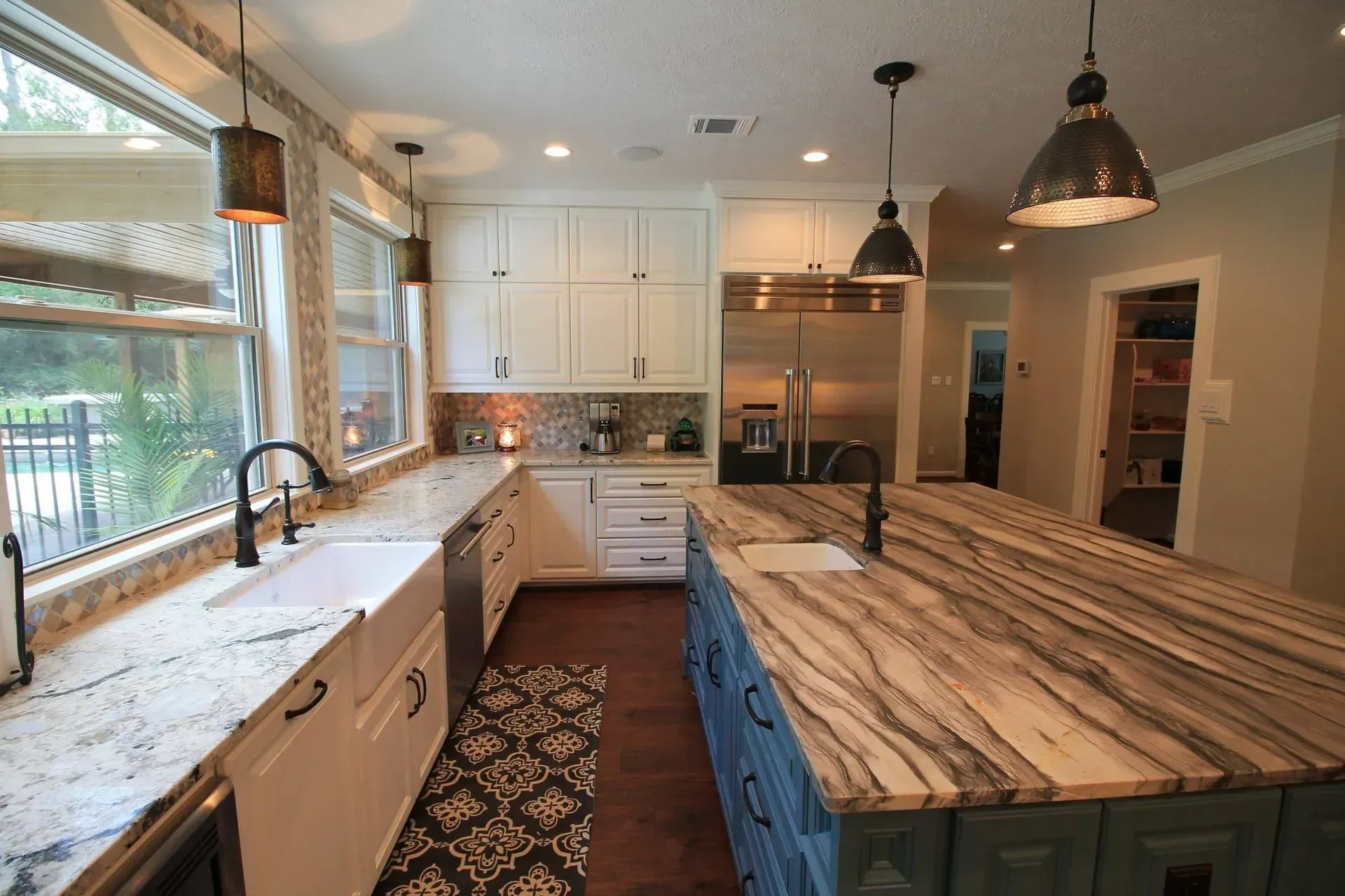 Bright kitchen with white cabinets, large island, farmhouse sink, and pendant lights