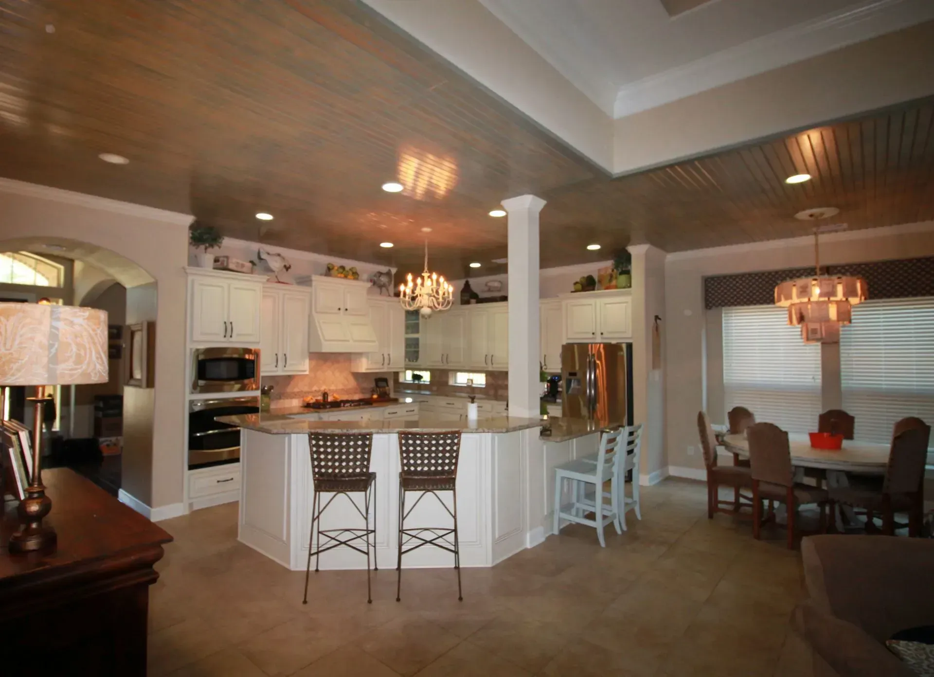 Open kitchen and dining area with white cabinets, island seating, and chandelier lighting
