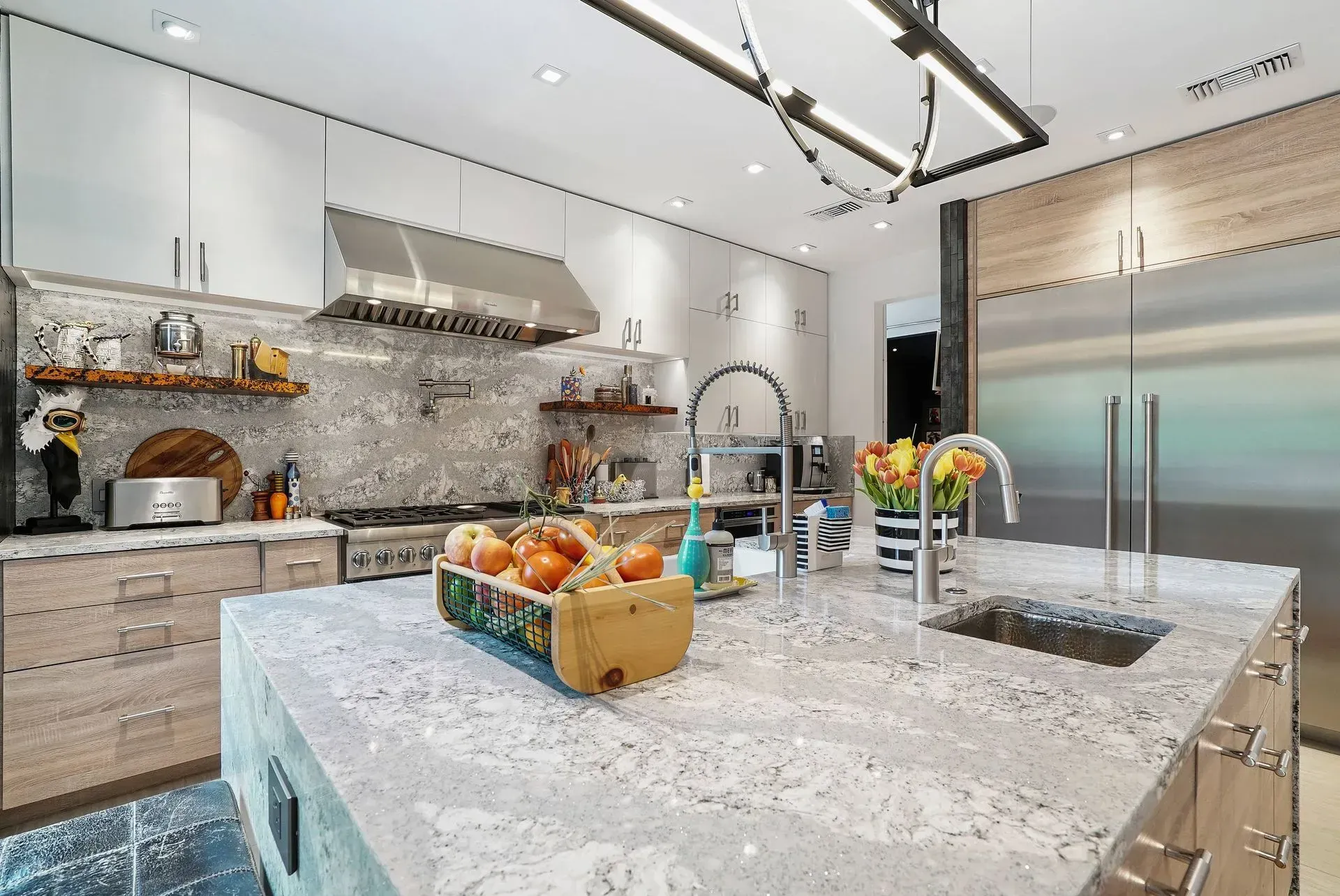 Modern kitchen with marble island, stainless steel appliances, and a fruit bowl