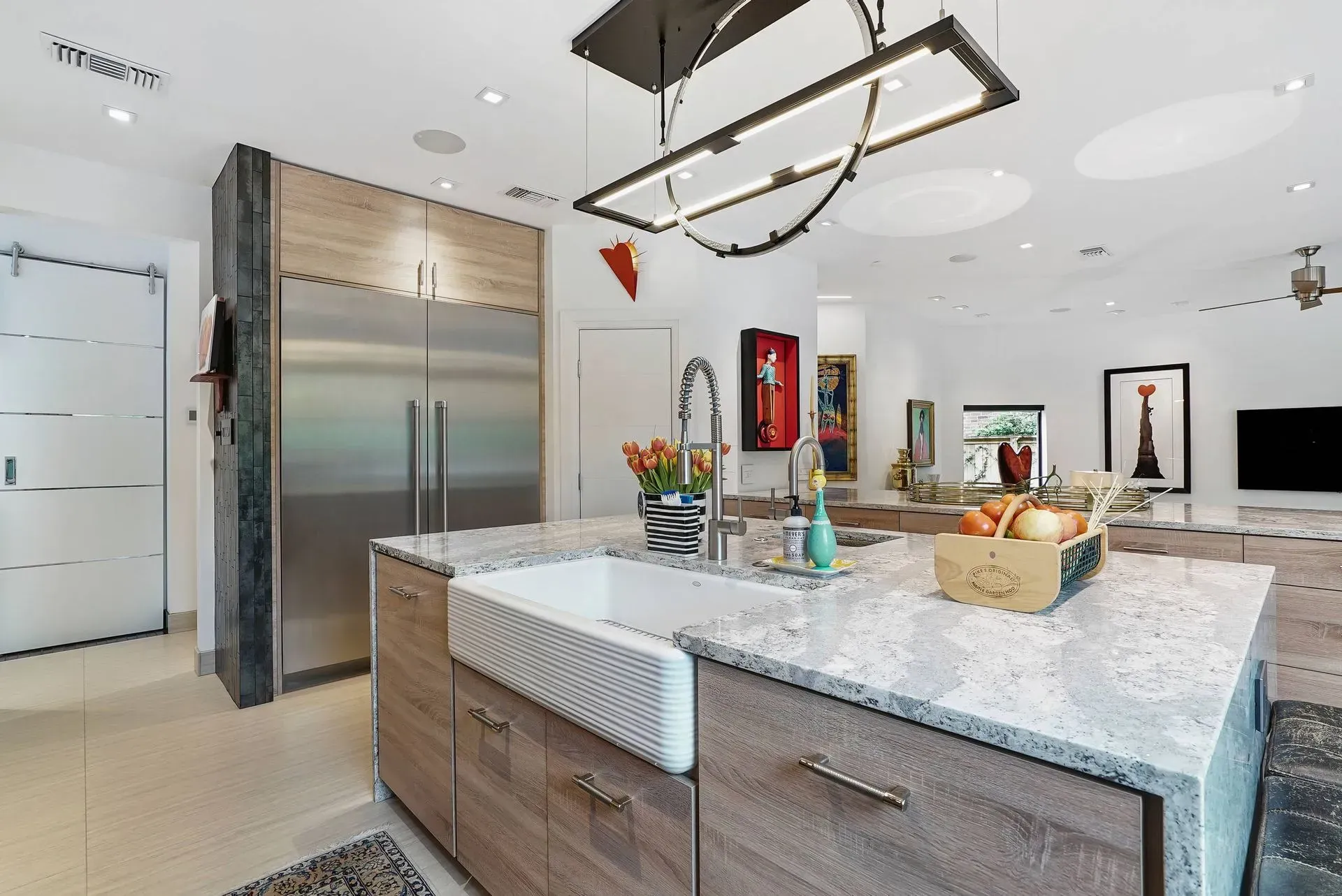 Modern kitchen with marble island, stainless steel fridge, and pendant lighting