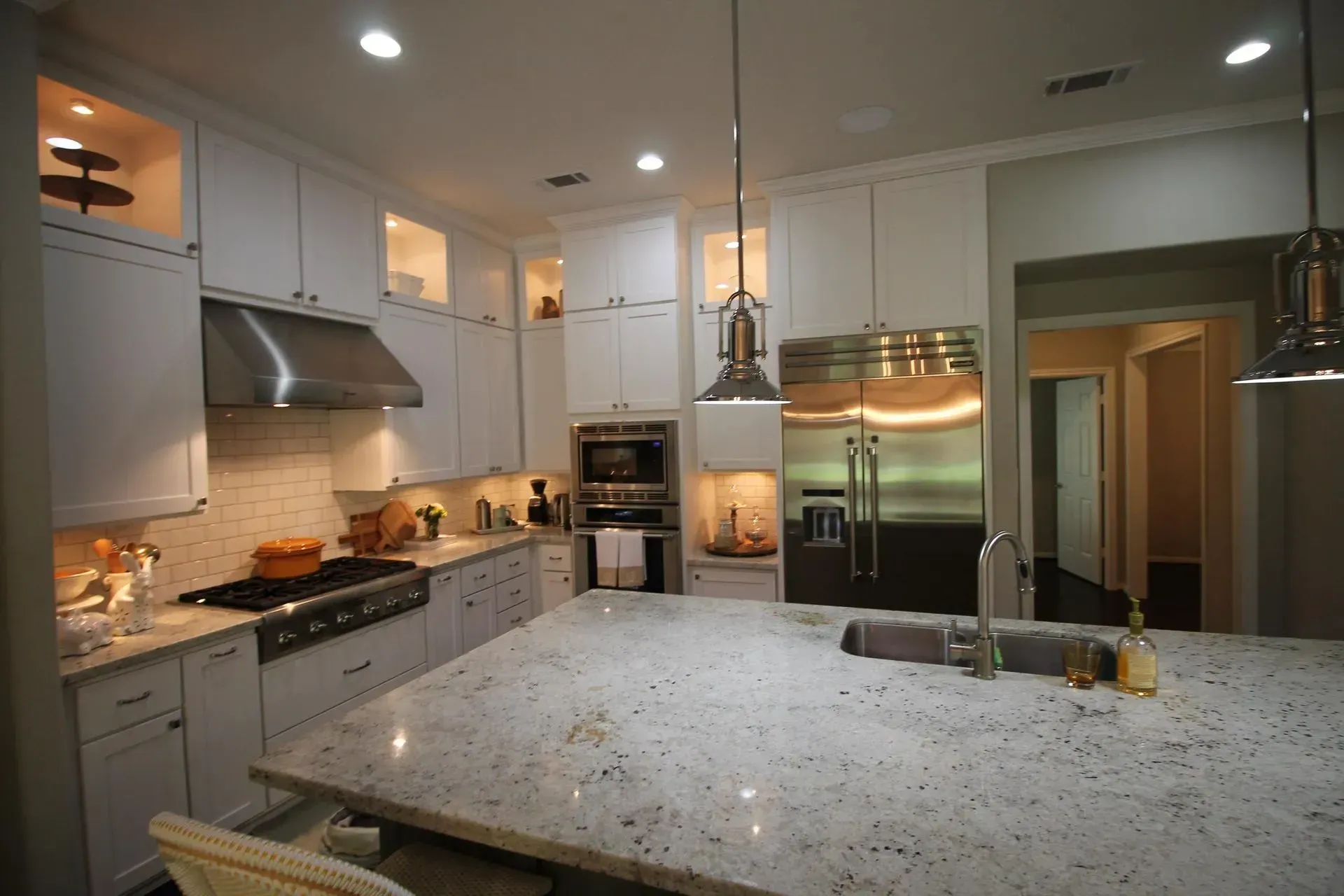 Bright modern kitchen with white cabinets, stainless steel appliances, and a large speckled island counter