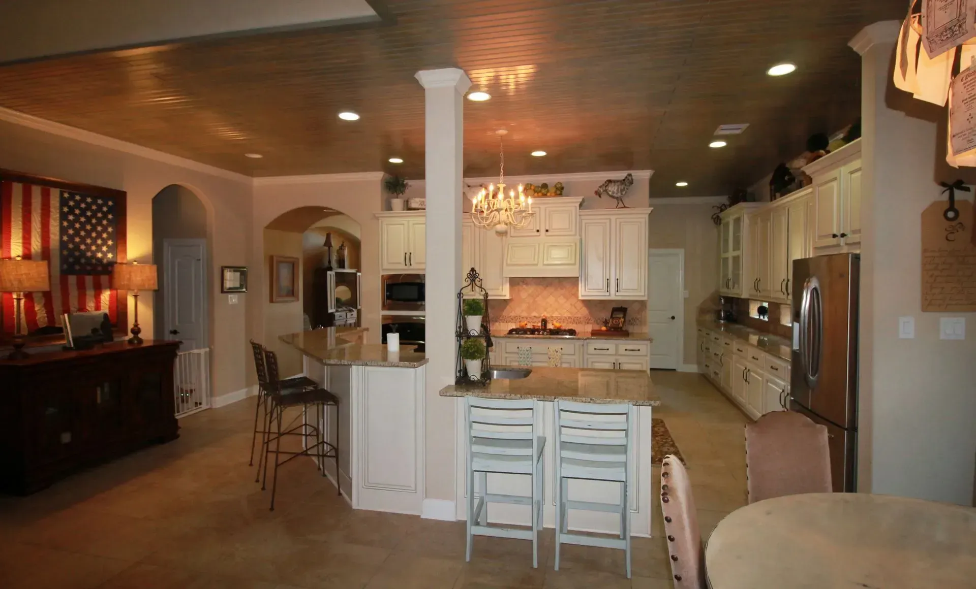 Spacious open-plan kitchen and dining area with white cabinets, island, and warm wood flooring