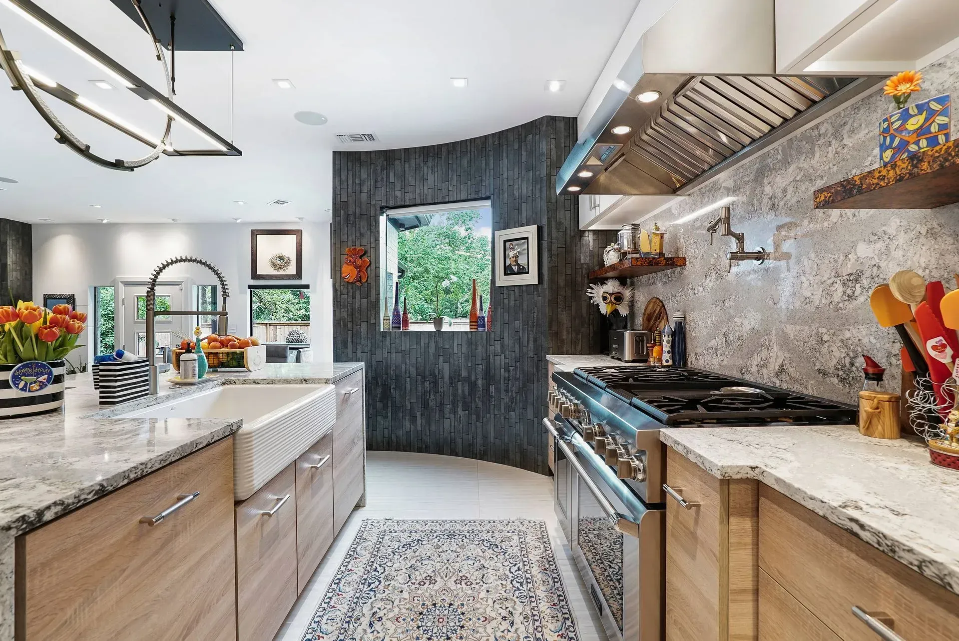 Modern kitchen with white countertops, wood cabinets, stainless appliances, and patterned rug