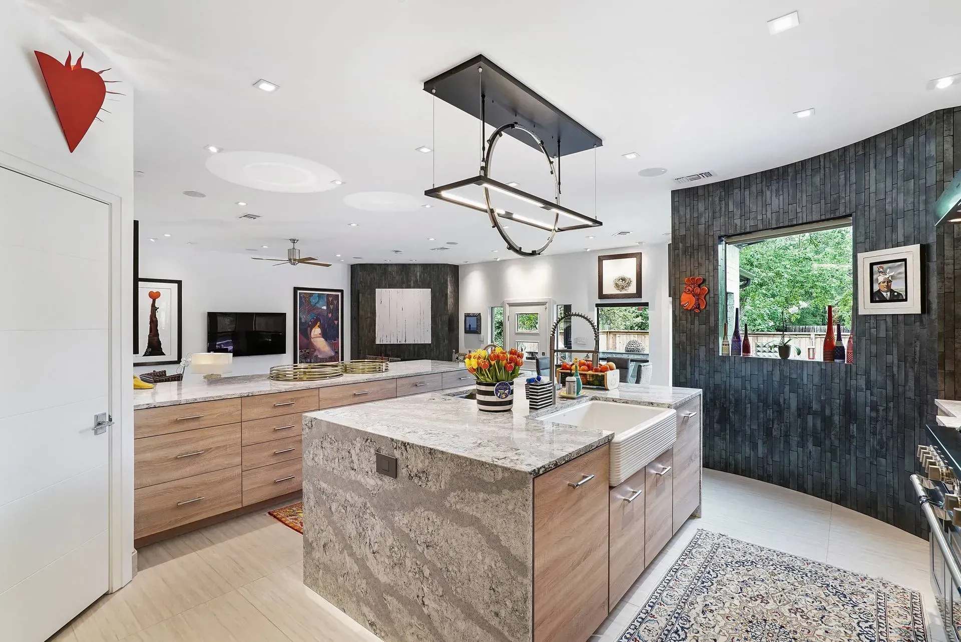 Bright modern kitchen with island, light wood cabinets, black accents, and large windows