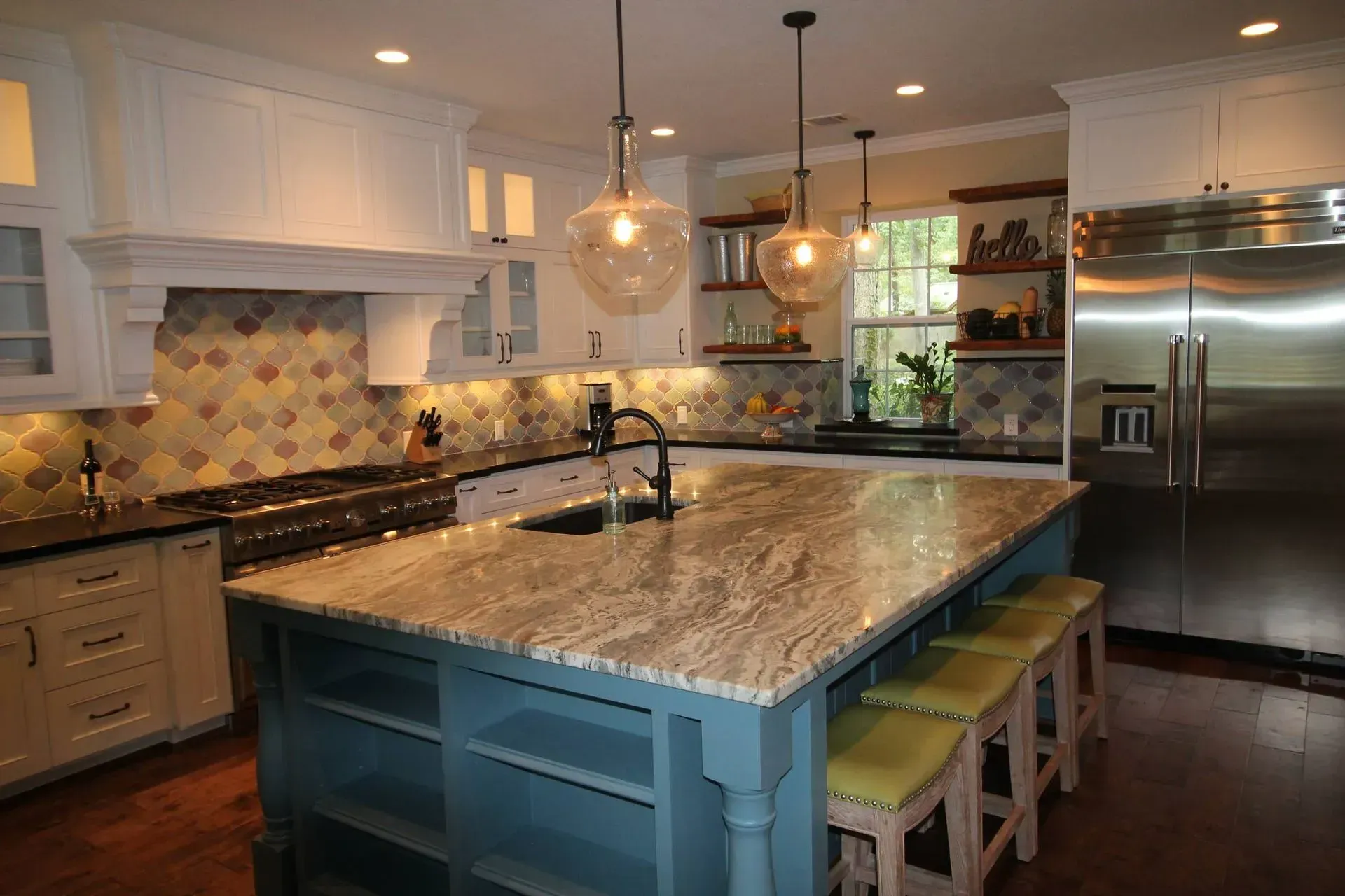 Modern kitchen with blue island, granite countertops, pendant lights, and stainless steel refrigerator