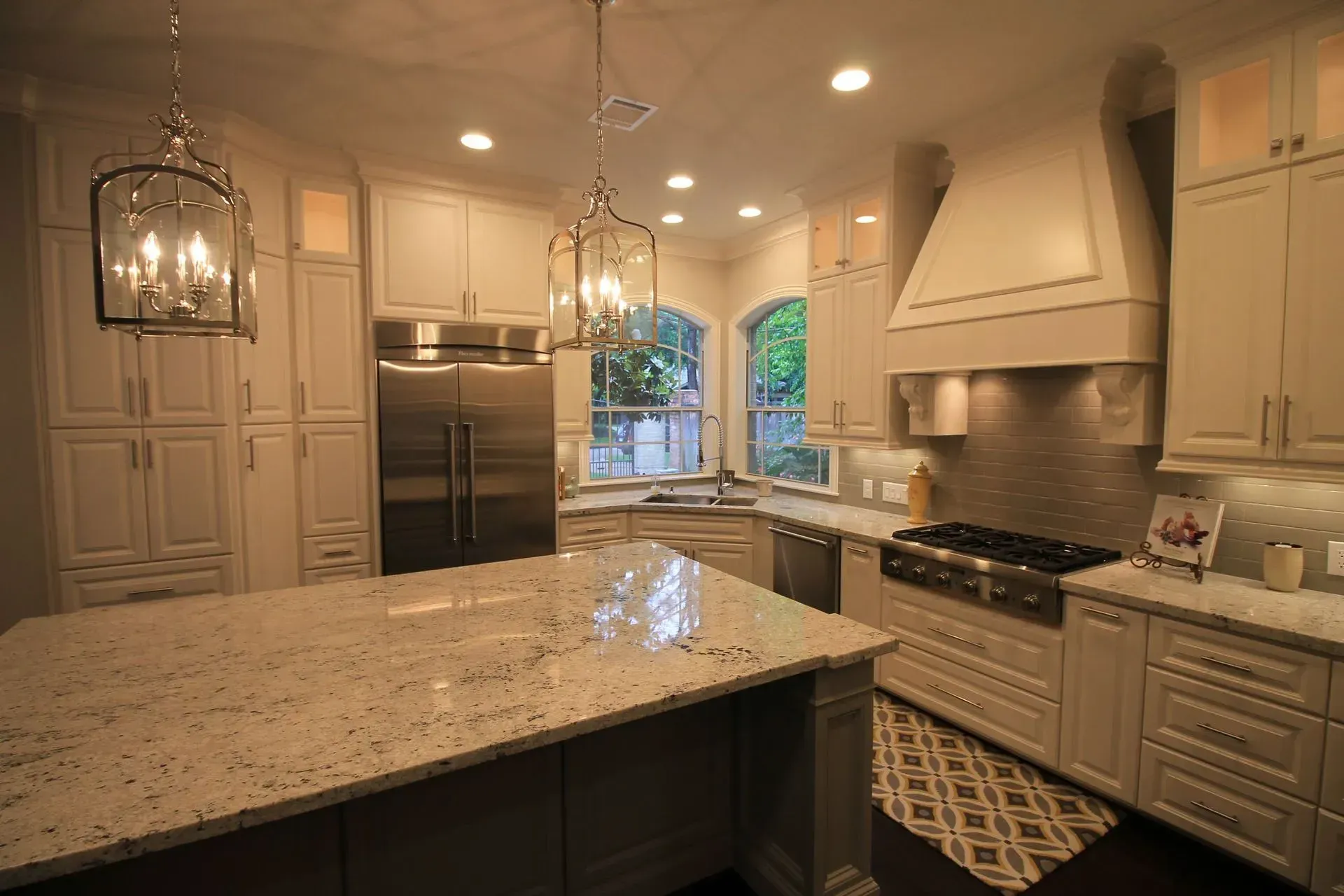 Modern kitchen with white cabinets, granite island, stainless appliances, and pendant lights