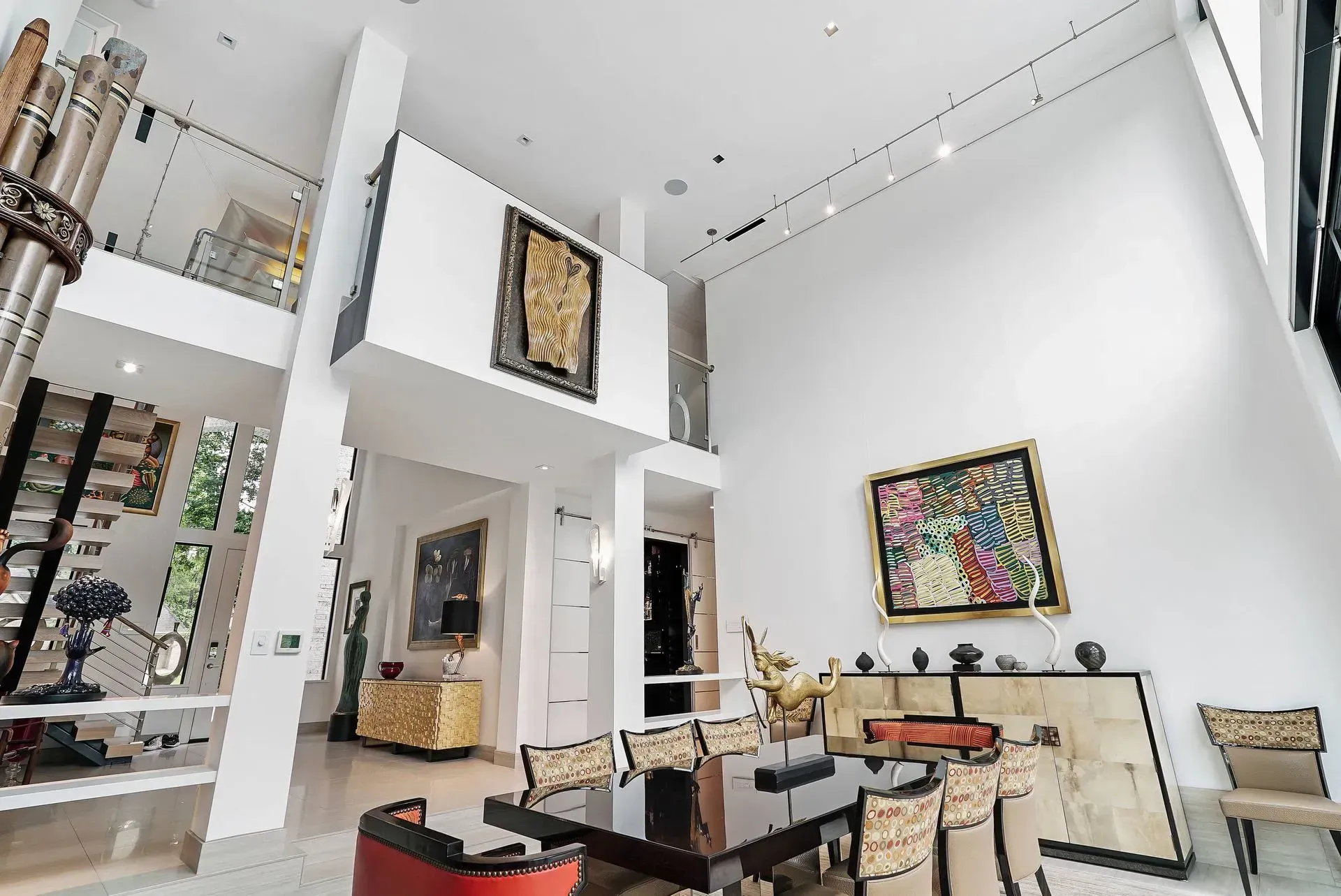 Bright modern living room with high white walls, colorful artwork, and minimalist furniture