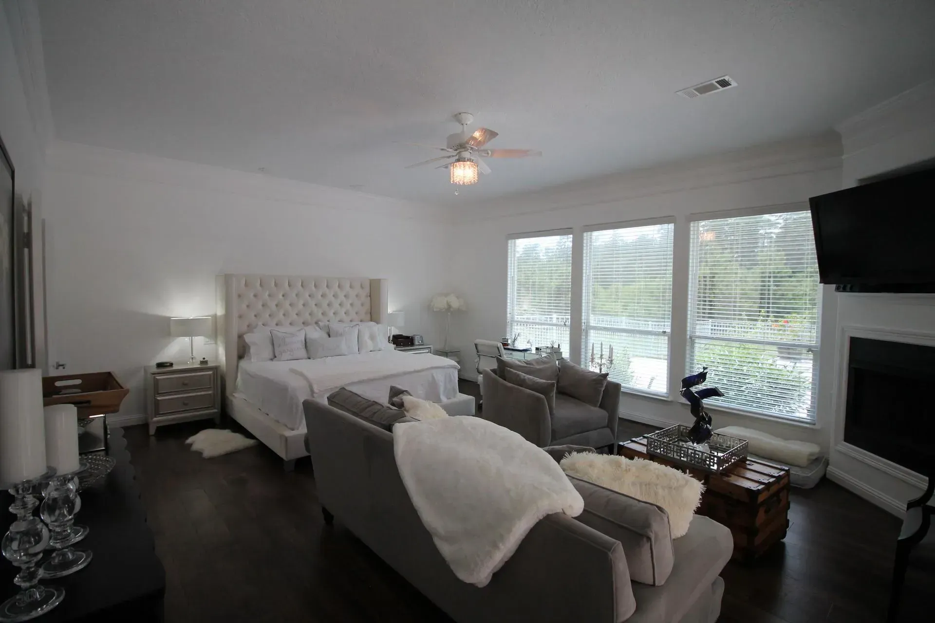 Bright modern bedroom with a bed, sofa, large windows, and wall-mounted TV