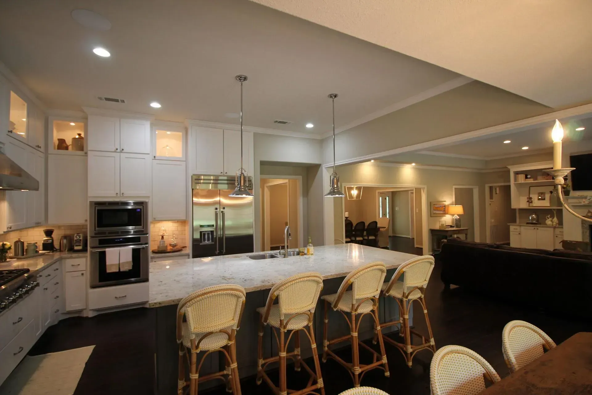 Modern kitchen with white cabinets, large island, pendant lights, and a barstool seating area