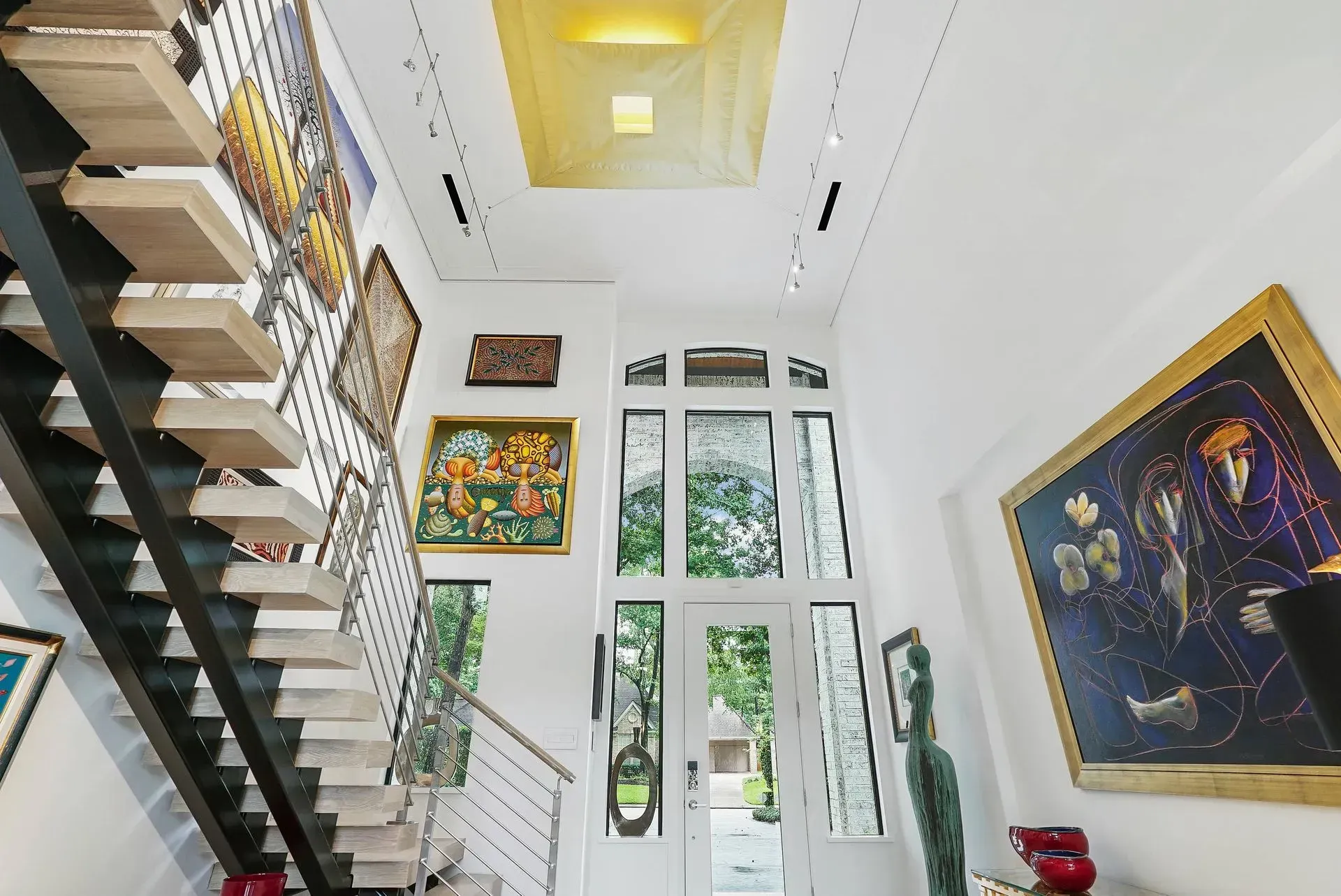 Modern home stairwell with white walls, large windows, and colorful framed artwork.