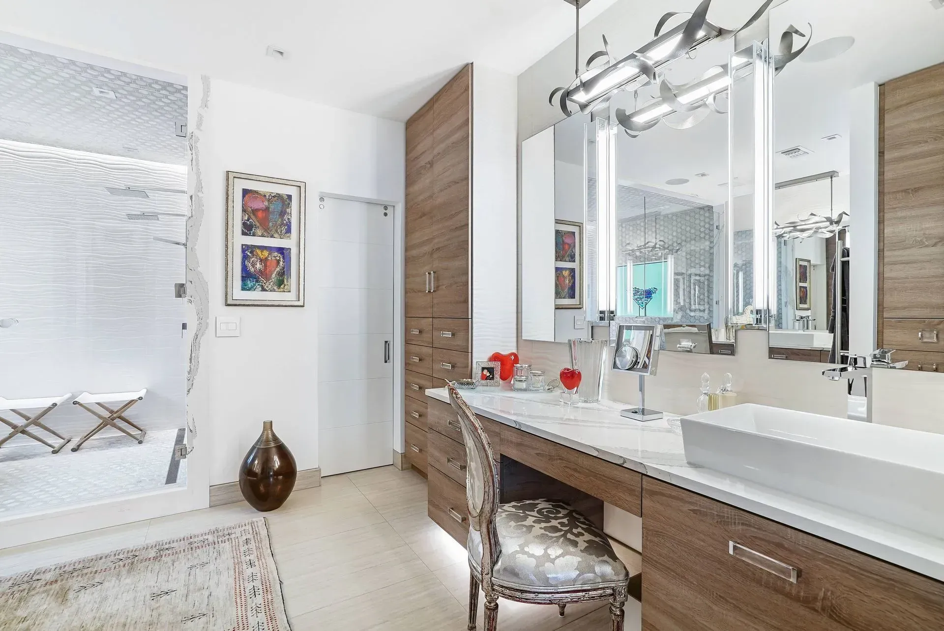 Bright modern bathroom with double vanity, large mirror, glass shower, and white decor