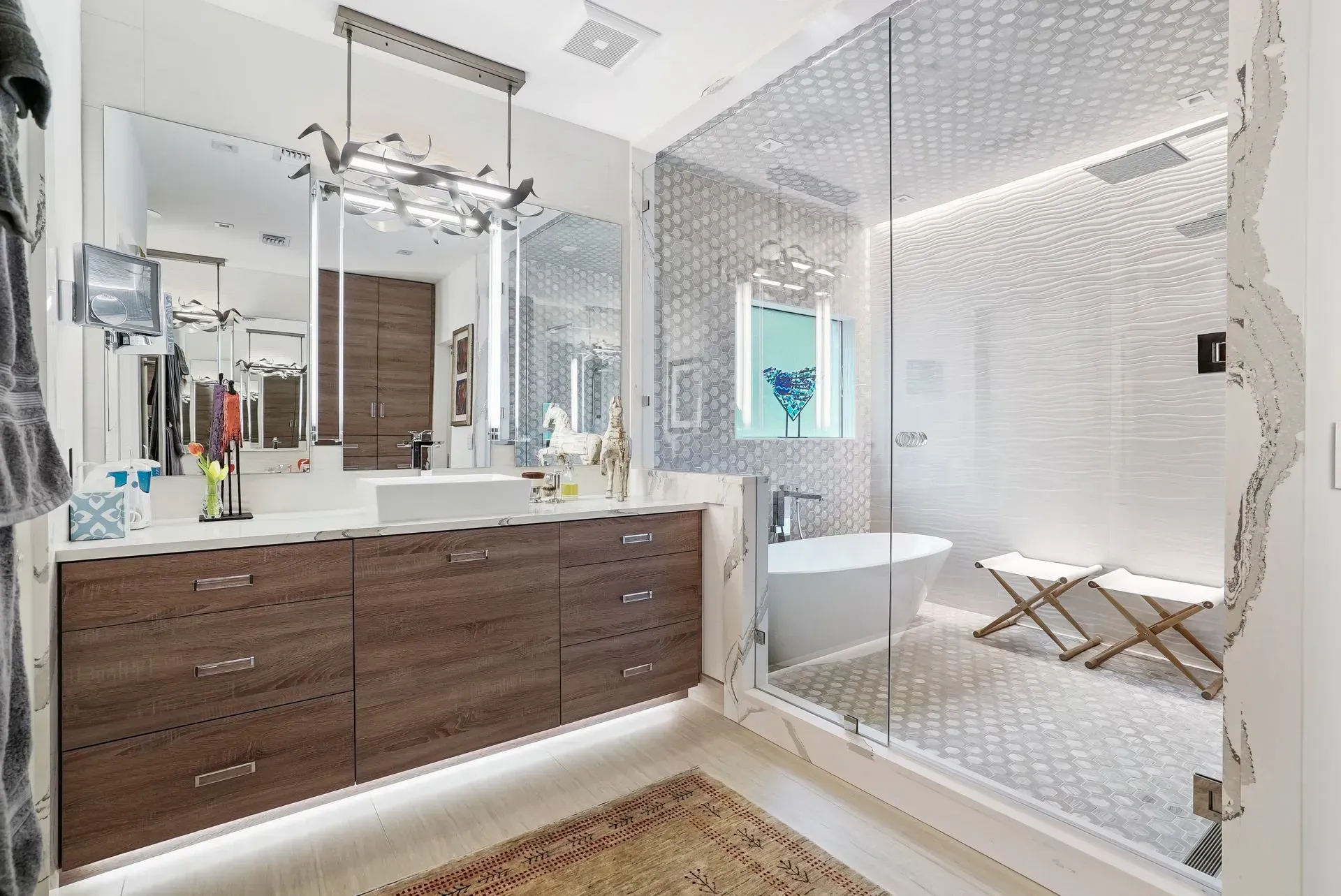 Modern white bathroom with double vanity, large mirror, and glass shower with patterned tile.