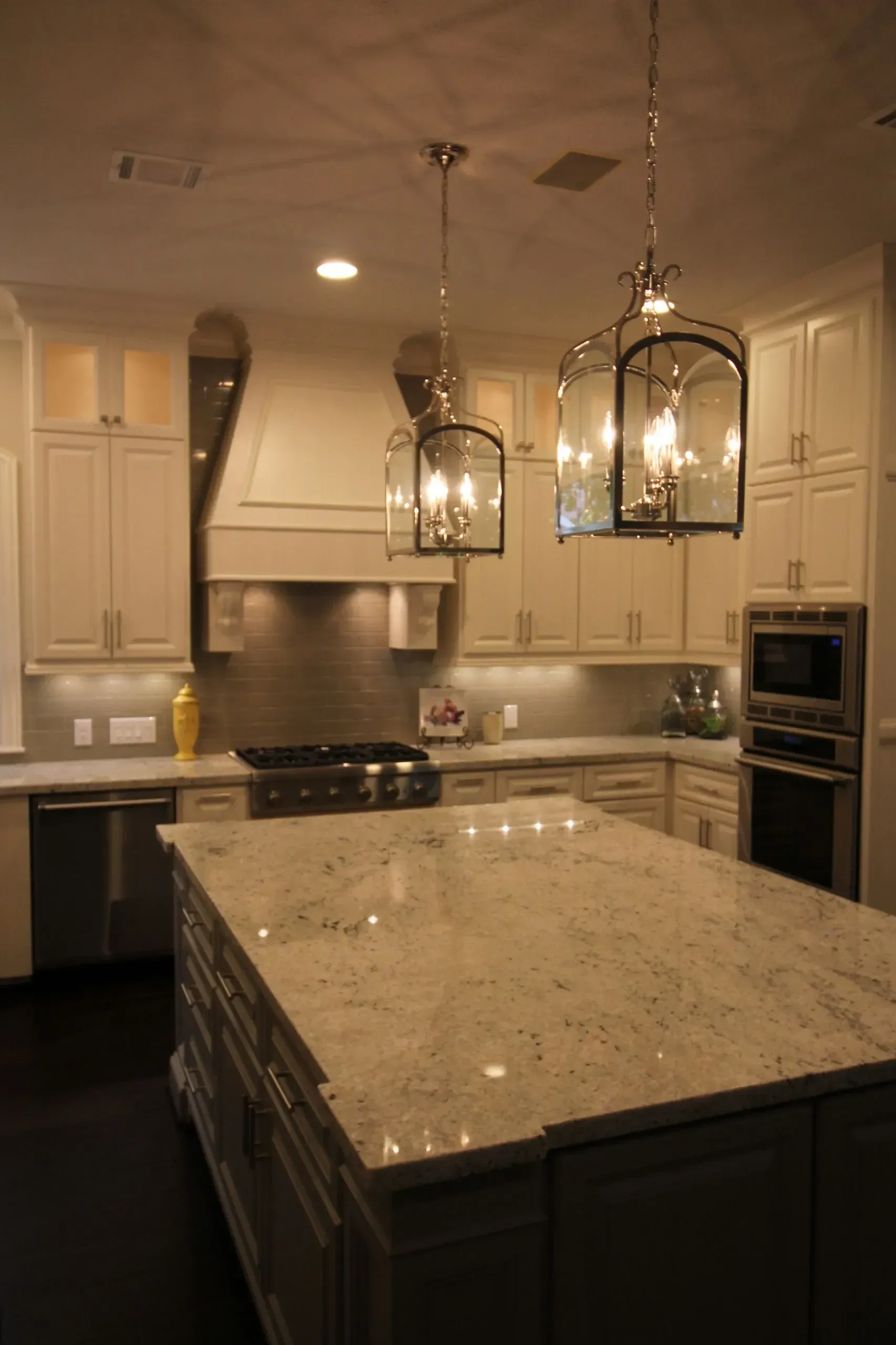 Elegant modern kitchen with dark cabinets, granite island, stainless appliances, and pendant lights