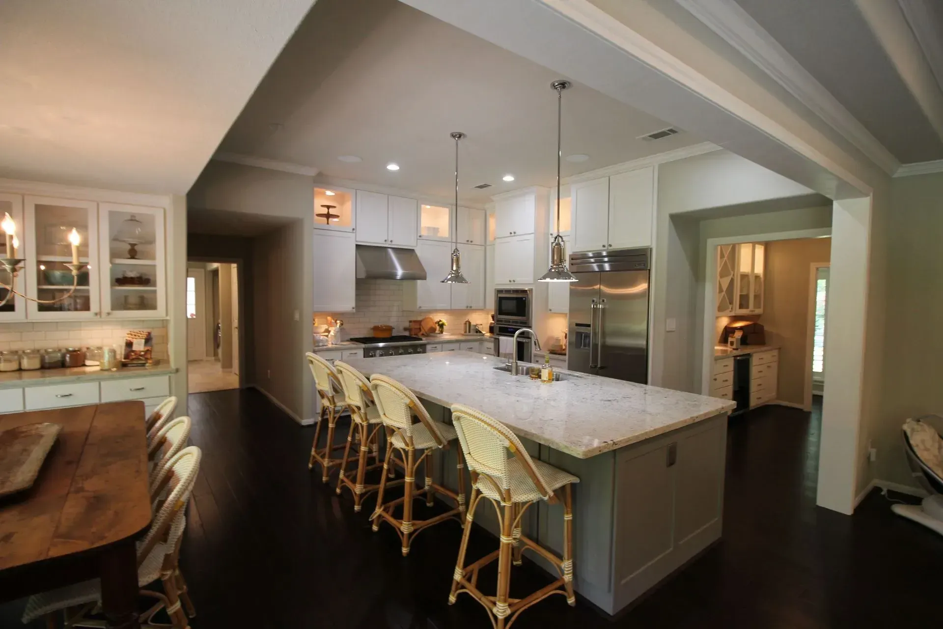 Modern kitchen with a marble island, gold bar stools, white cabinets, and stainless steel appliances.