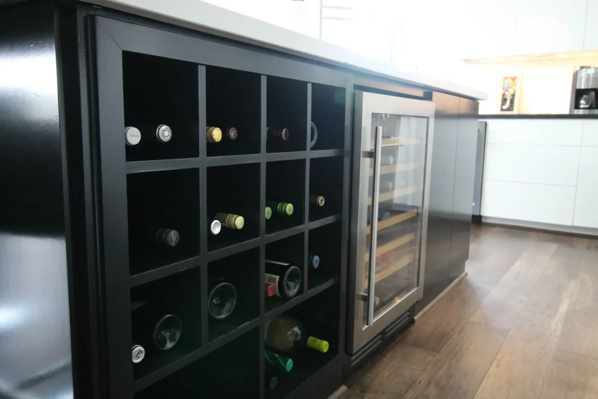 Black wine cabinet with bottles and glass-door refrigerator in a modern kitchen