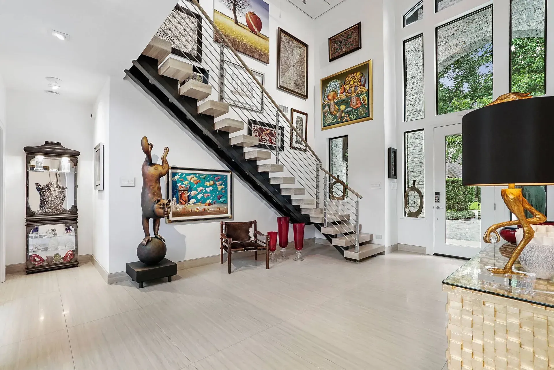 Modern foyer with a floating staircase, white walls, artwork, and large windows.