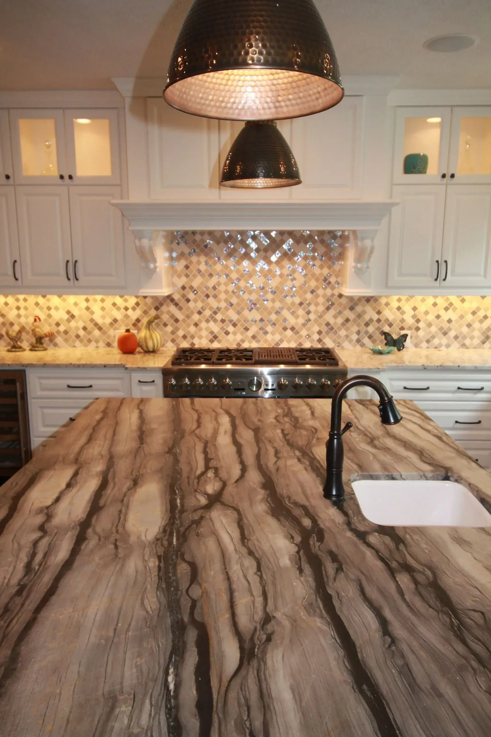 Modern kitchen with marble island, white cabinets, mosaic backsplash, and two pendant lights