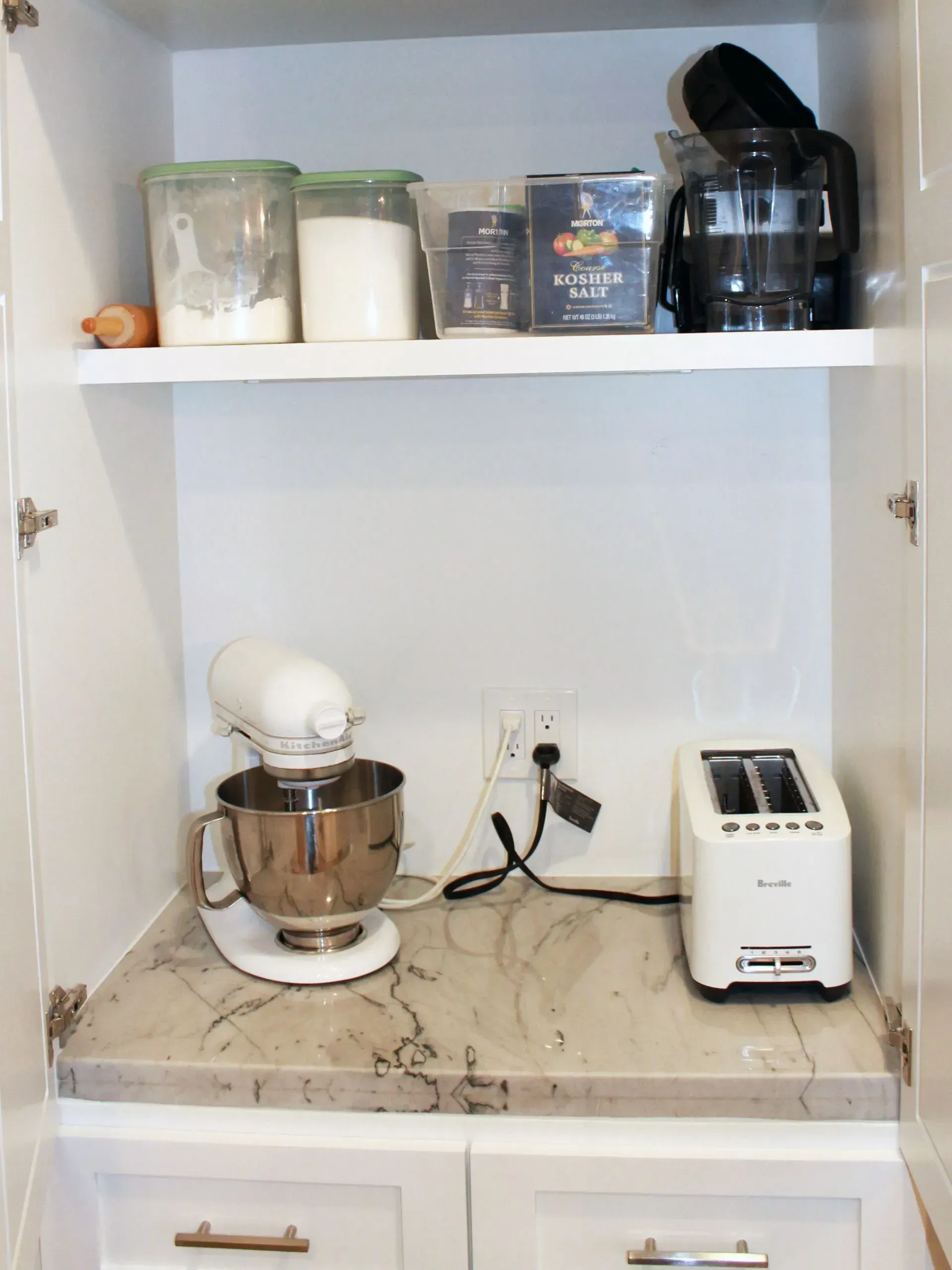 Kitchen shelf with pantry jars, a stand mixer on the counter, and a toaster next to an outlet.