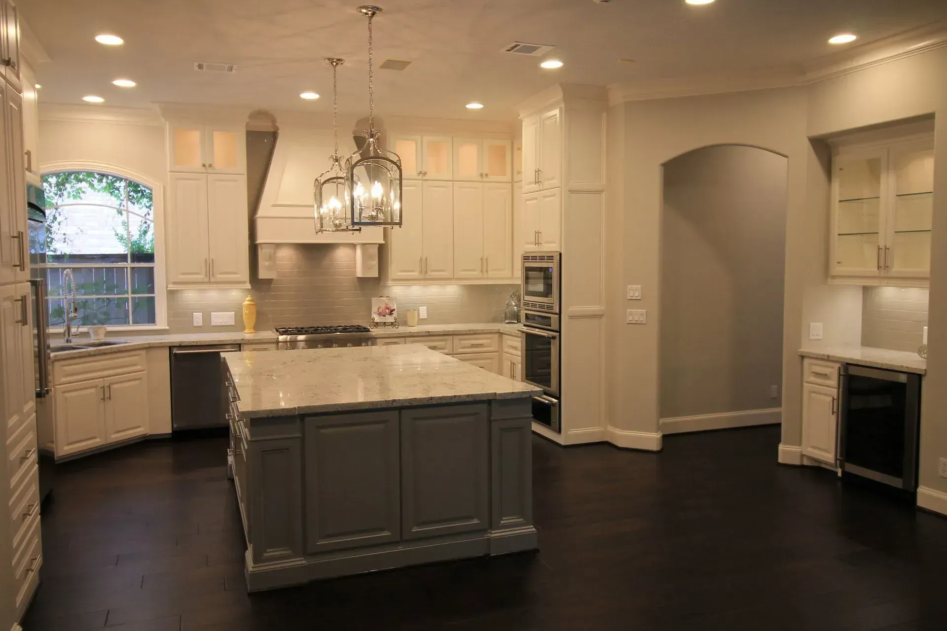 Spacious white kitchen with dark hardwood floors, center island, and built-in appliances.