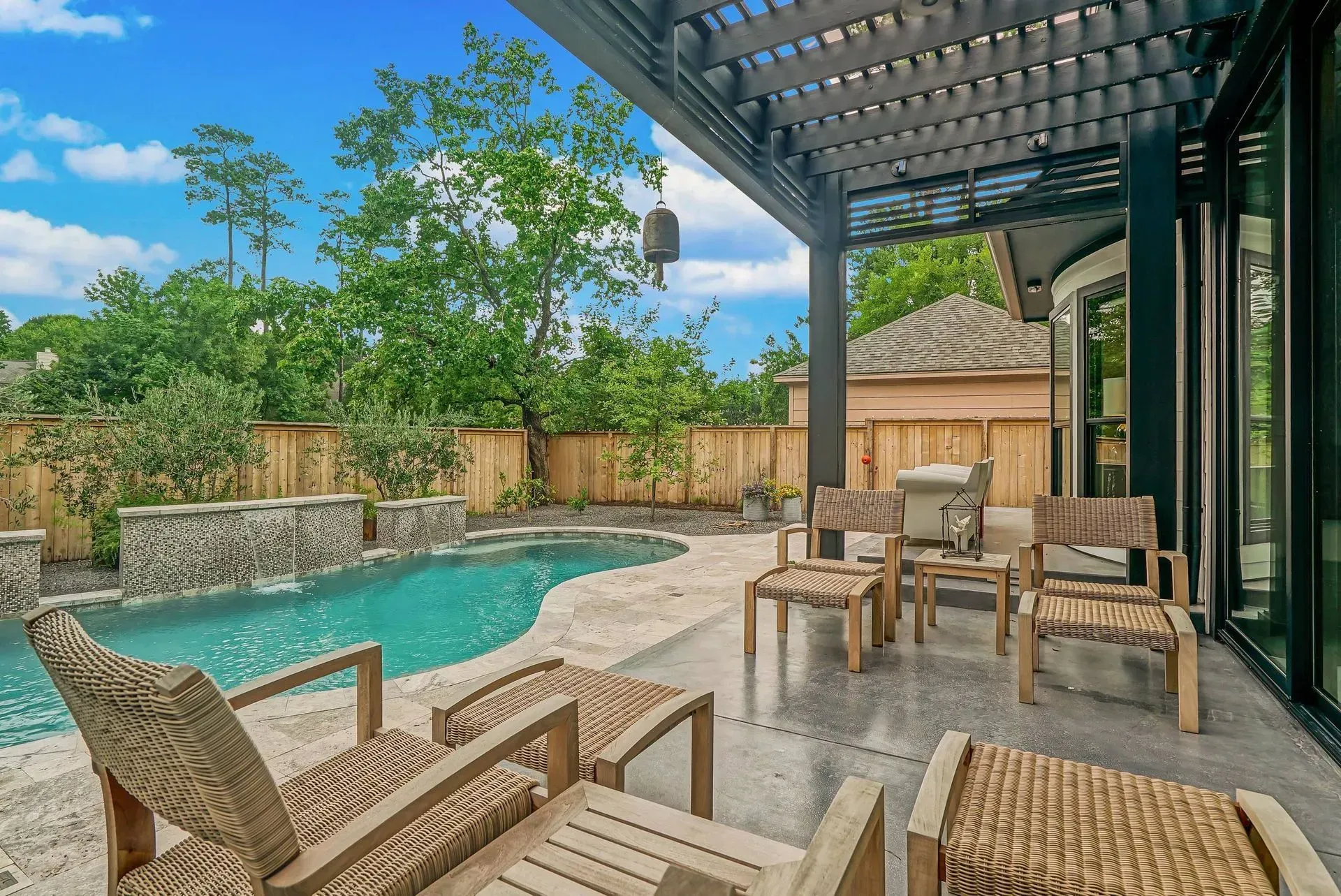 Patio with a pool, lounge chairs, and covered seating beside a modern house