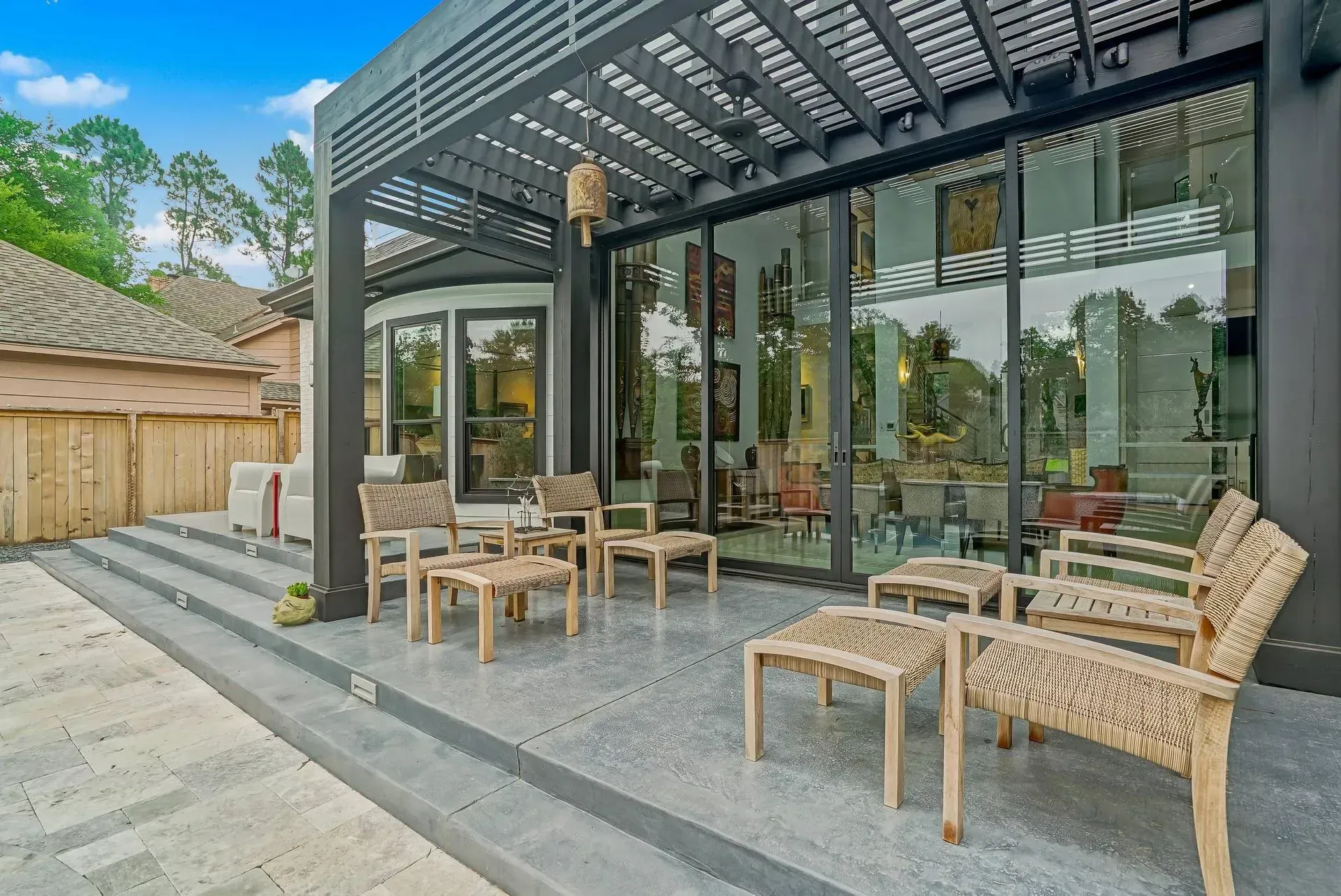 Outdoor patio with wicker chairs and tables beside a modern glass-walled building