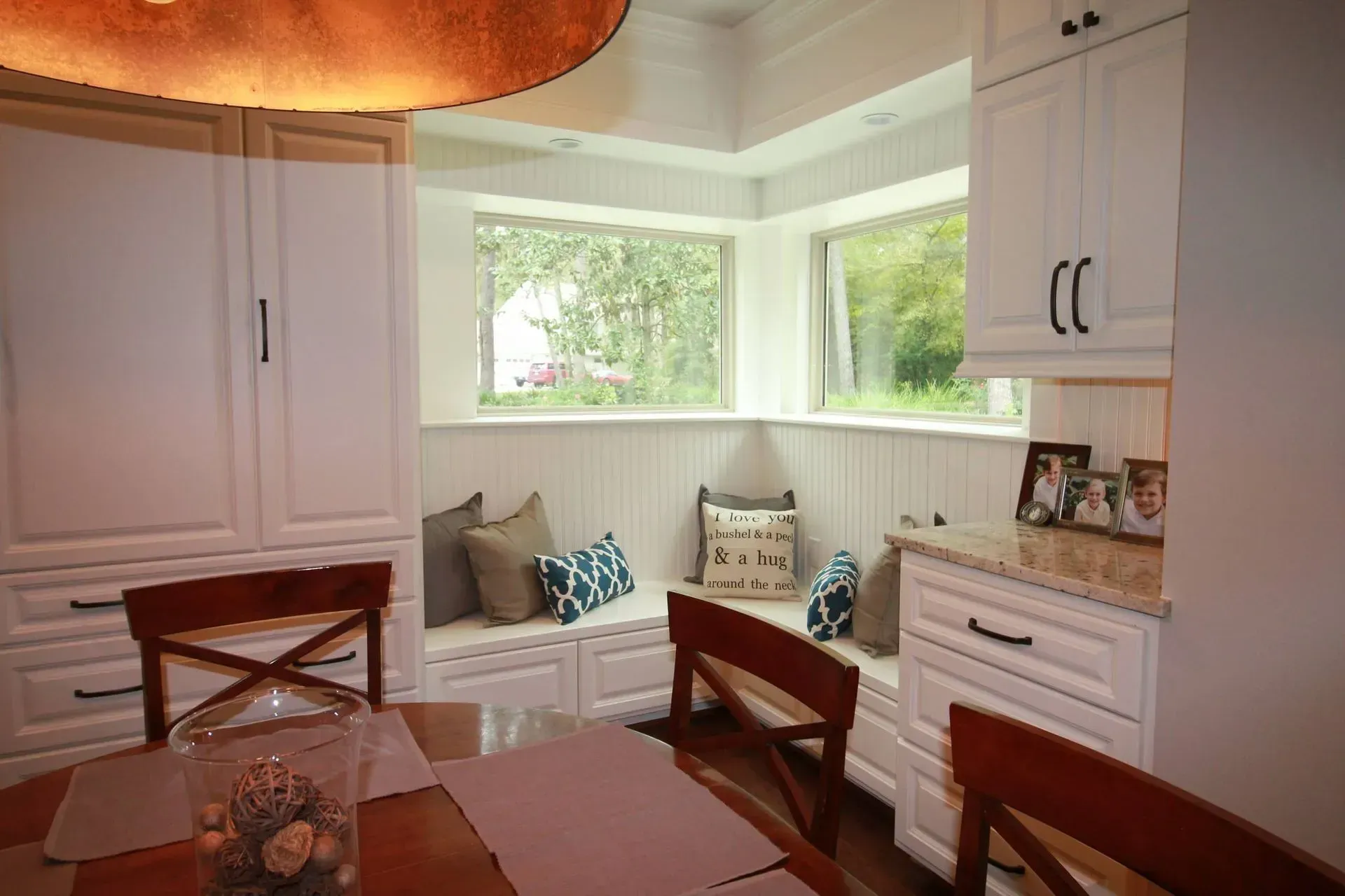 Bright dining nook with built-in bench seating, white cabinets, and large corner windows.