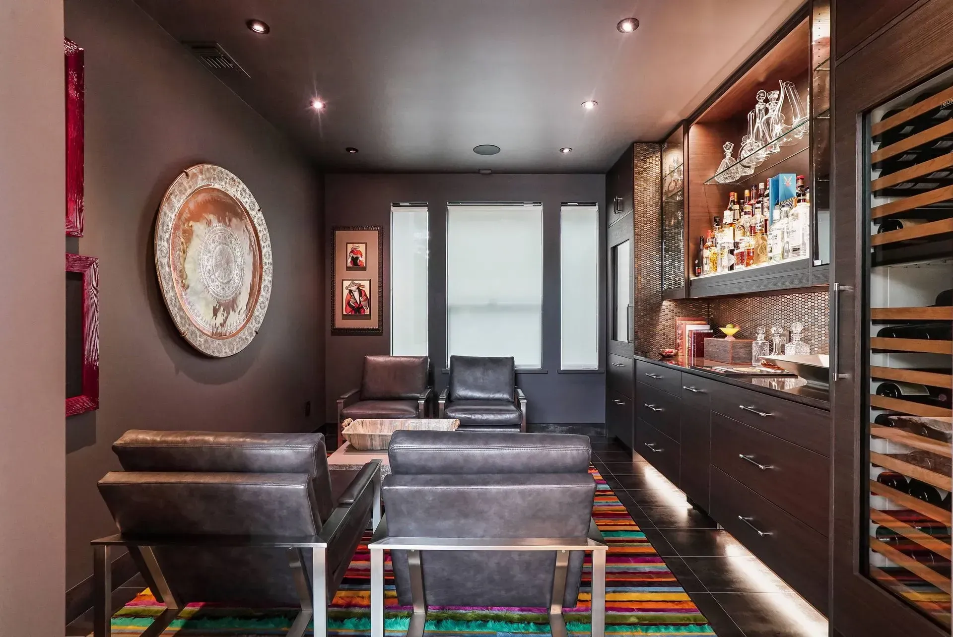 Modern lounge with black leather chairs, wall art, and a built-in wine display.