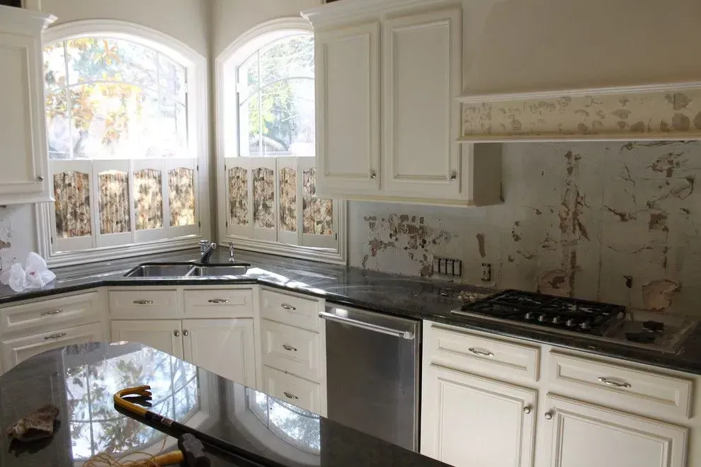 Bright cream kitchen with black granite countertops, white cabinets, and large windows over the sink.