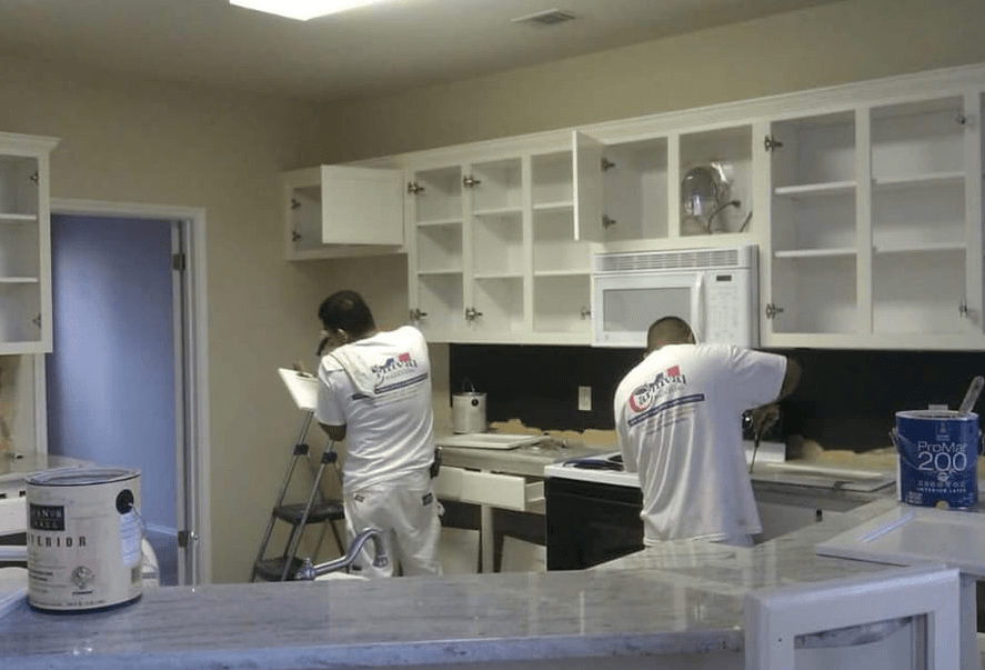 Workers installing cabinets in a kitchen under renovation