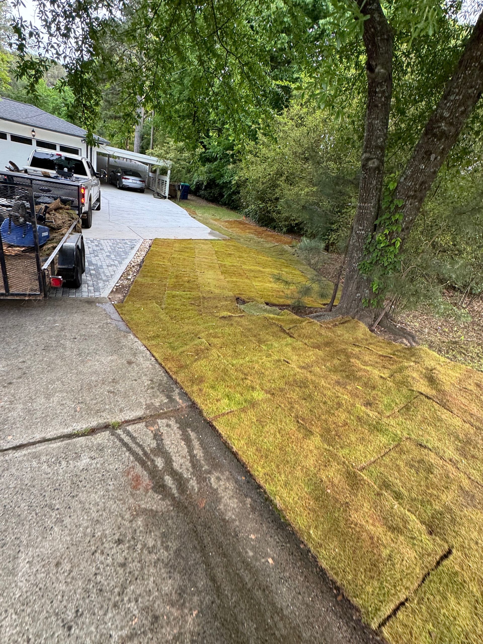 A trailer is parked on the side of a road next to a lush green lawn.