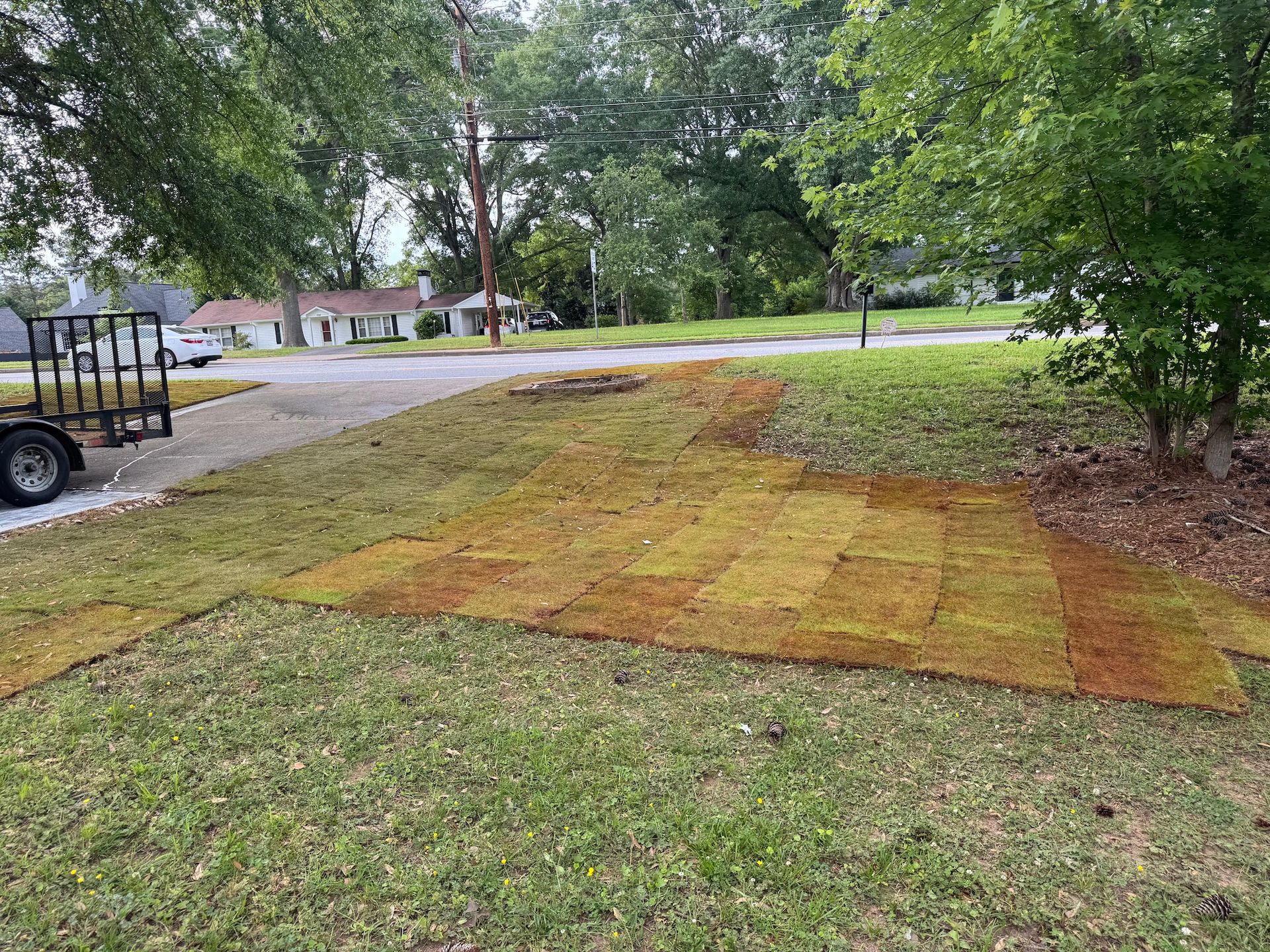 A trailer is parked in front of a lush green lawn.