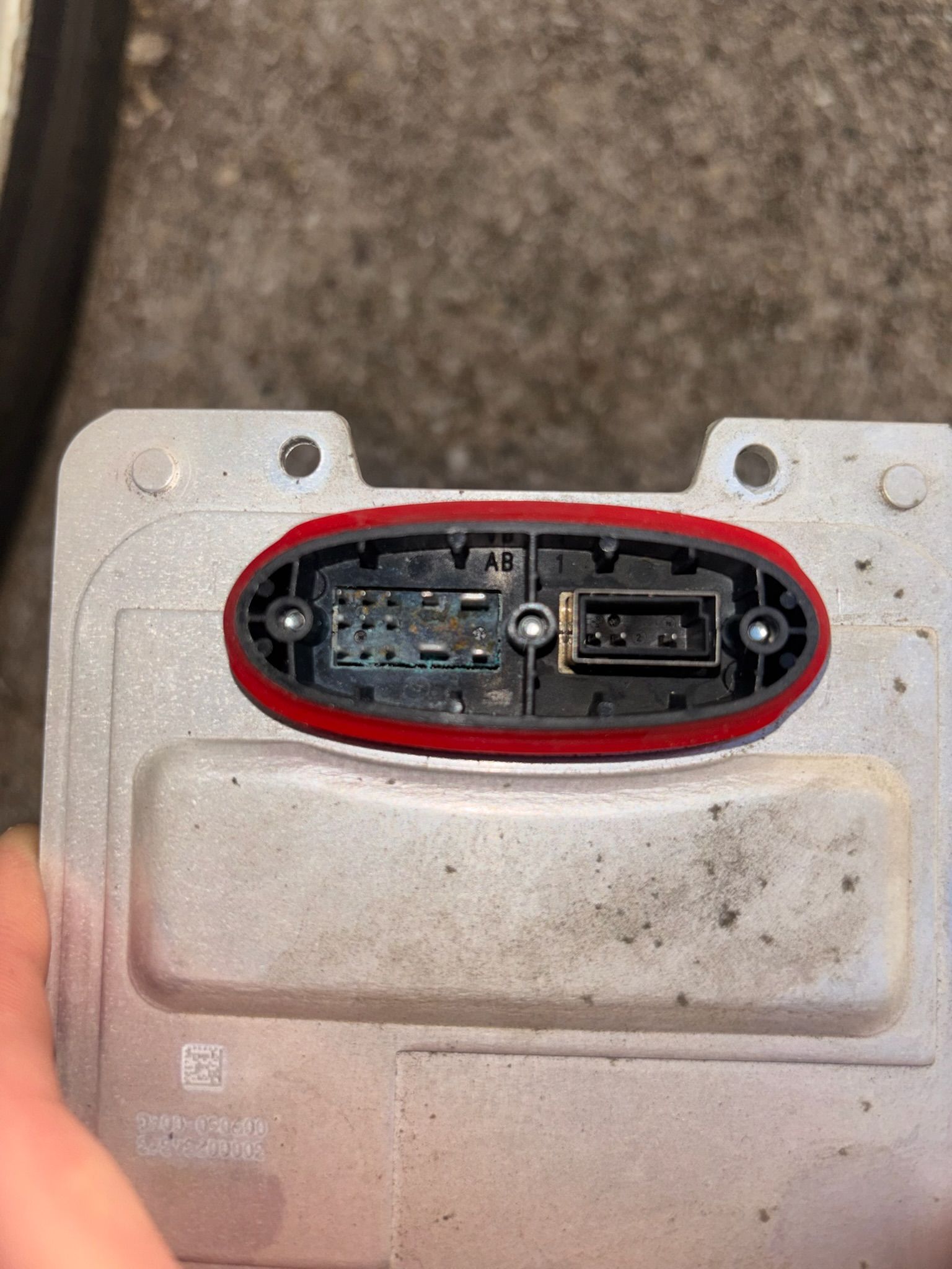 Close-up of a metal panel with an oval red-outlined opening exposing two electronic connectors.