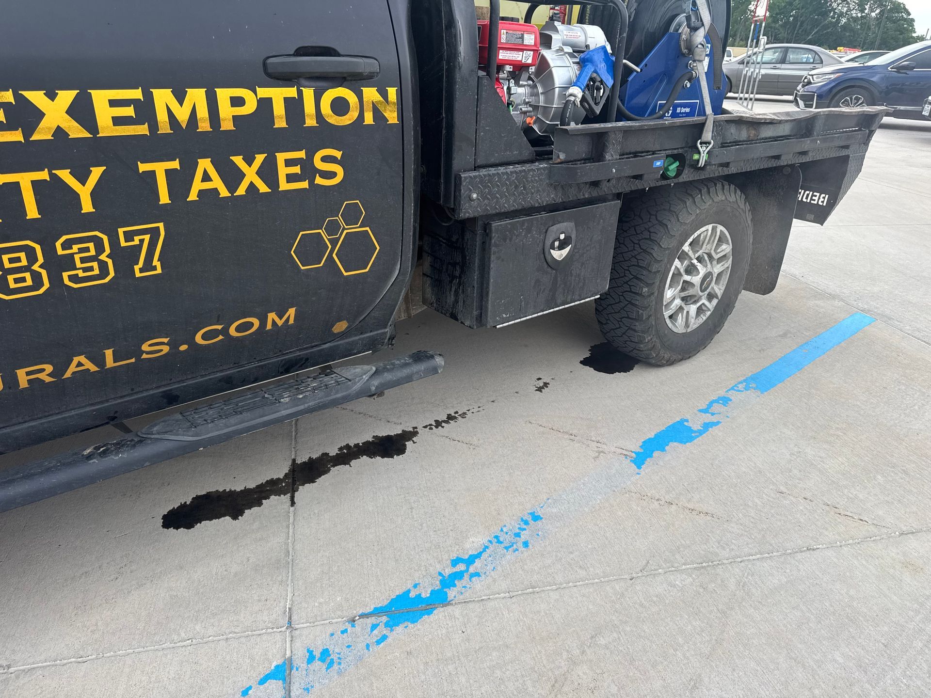 Black pickup truck with “EXEMPT” tax sign parked on street beside blue pavement markings.