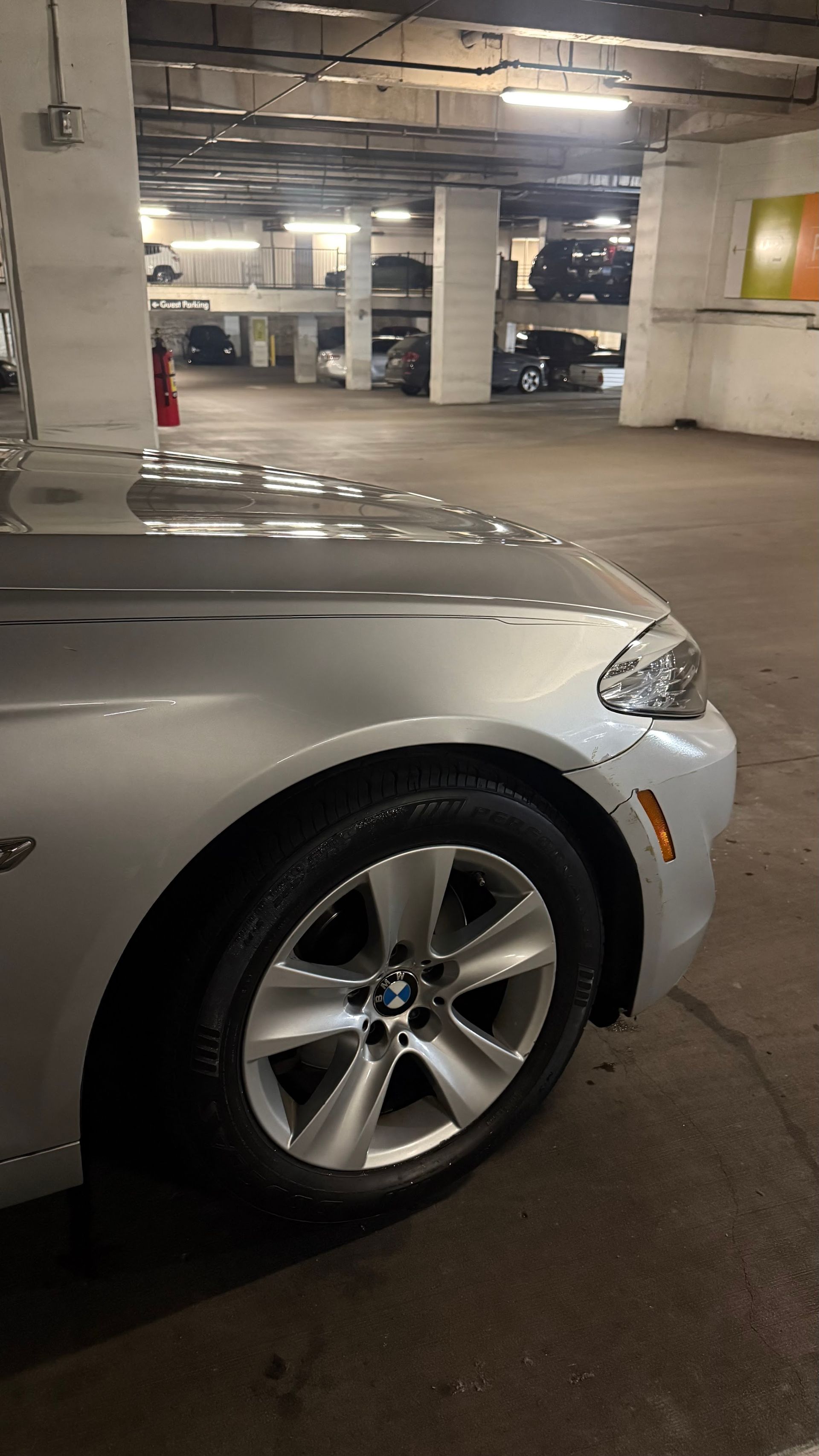 Silver BMW parked in a dimly lit concrete garage, front-left view.