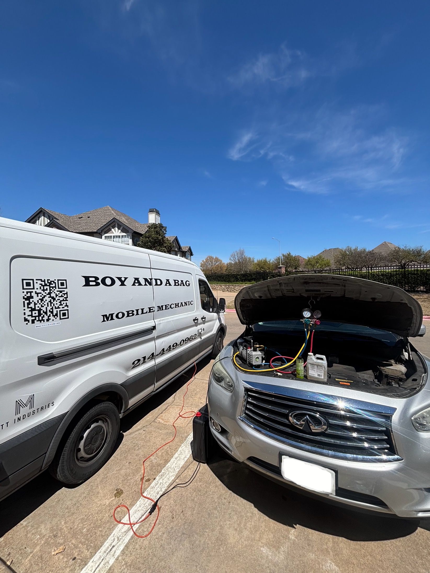 Two parked vans on a sunny street, one with its hood open for maintenance.