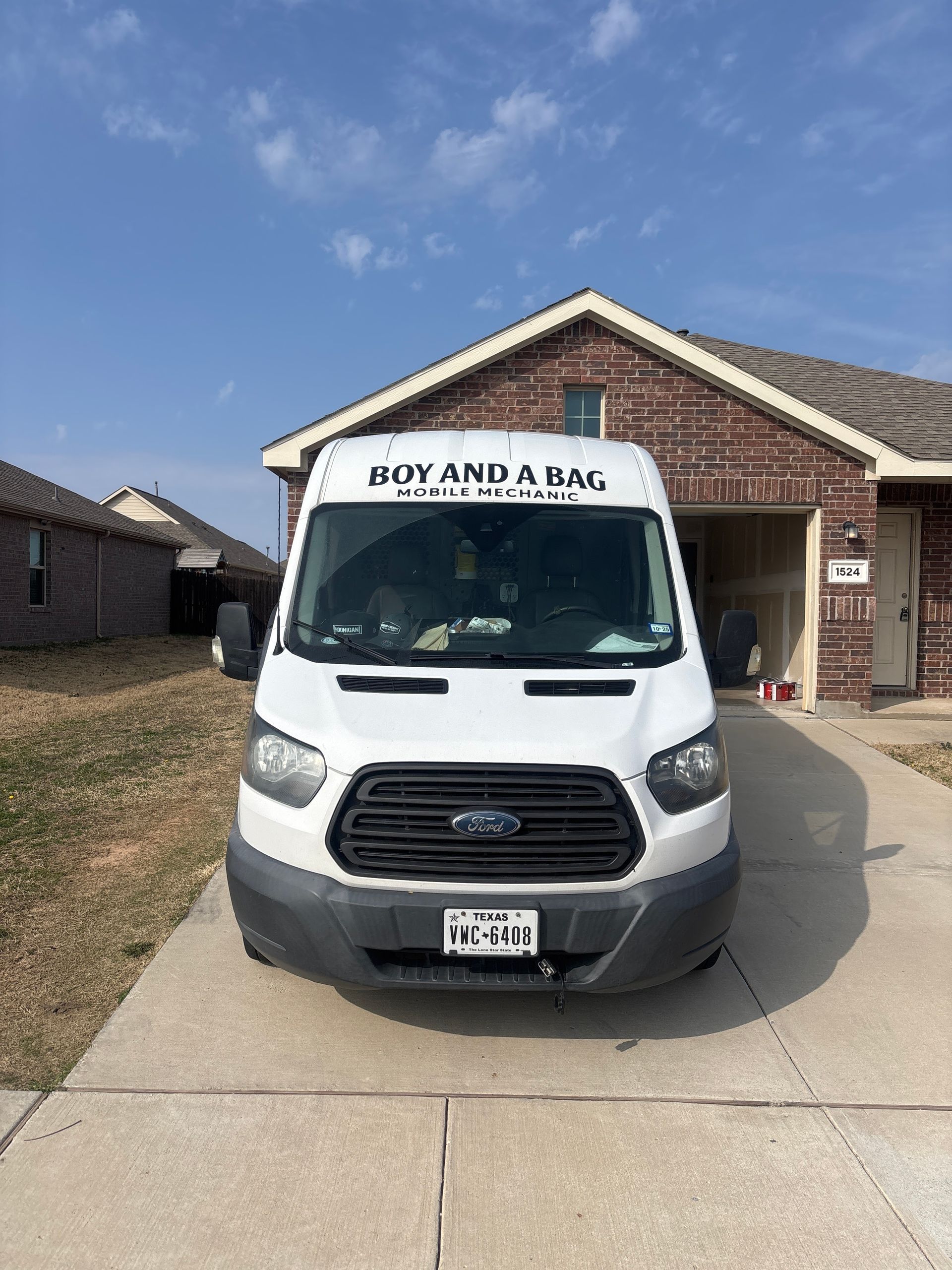 White Ford van parked in a driveway outside a brick house on a sunny day
