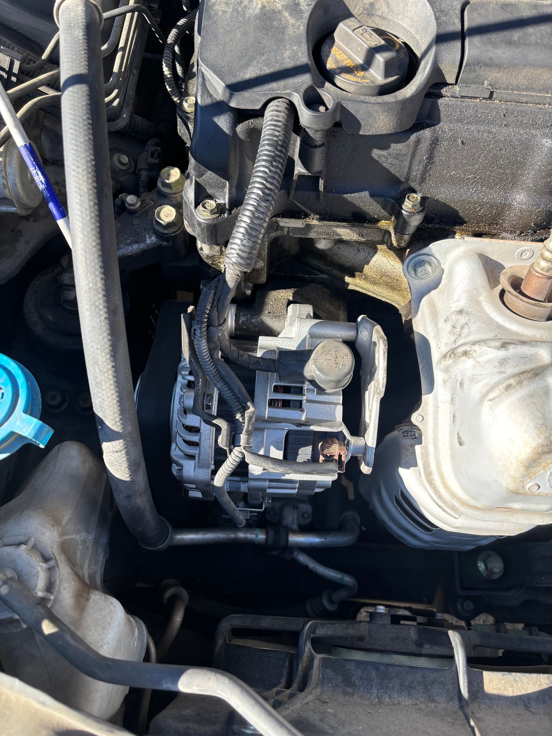 Close-up of a car engine bay showing a corroded battery terminal and wiring components