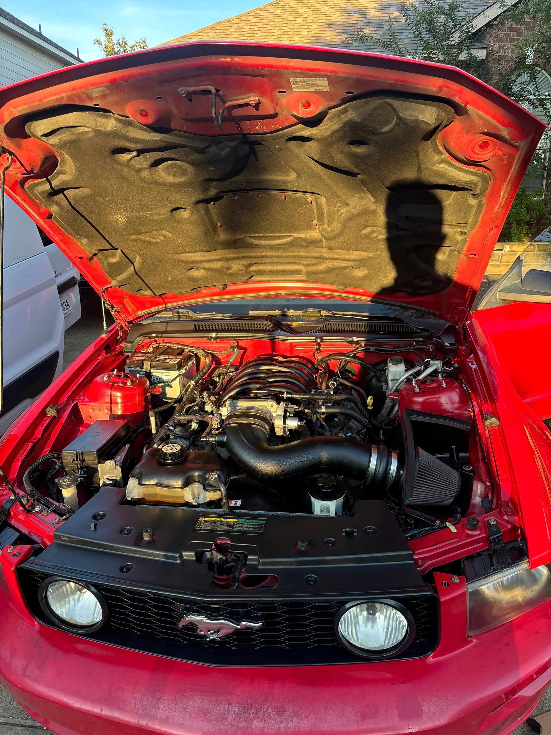 Red car with hood open, showing a modified engine bay and grille-mounted lights.