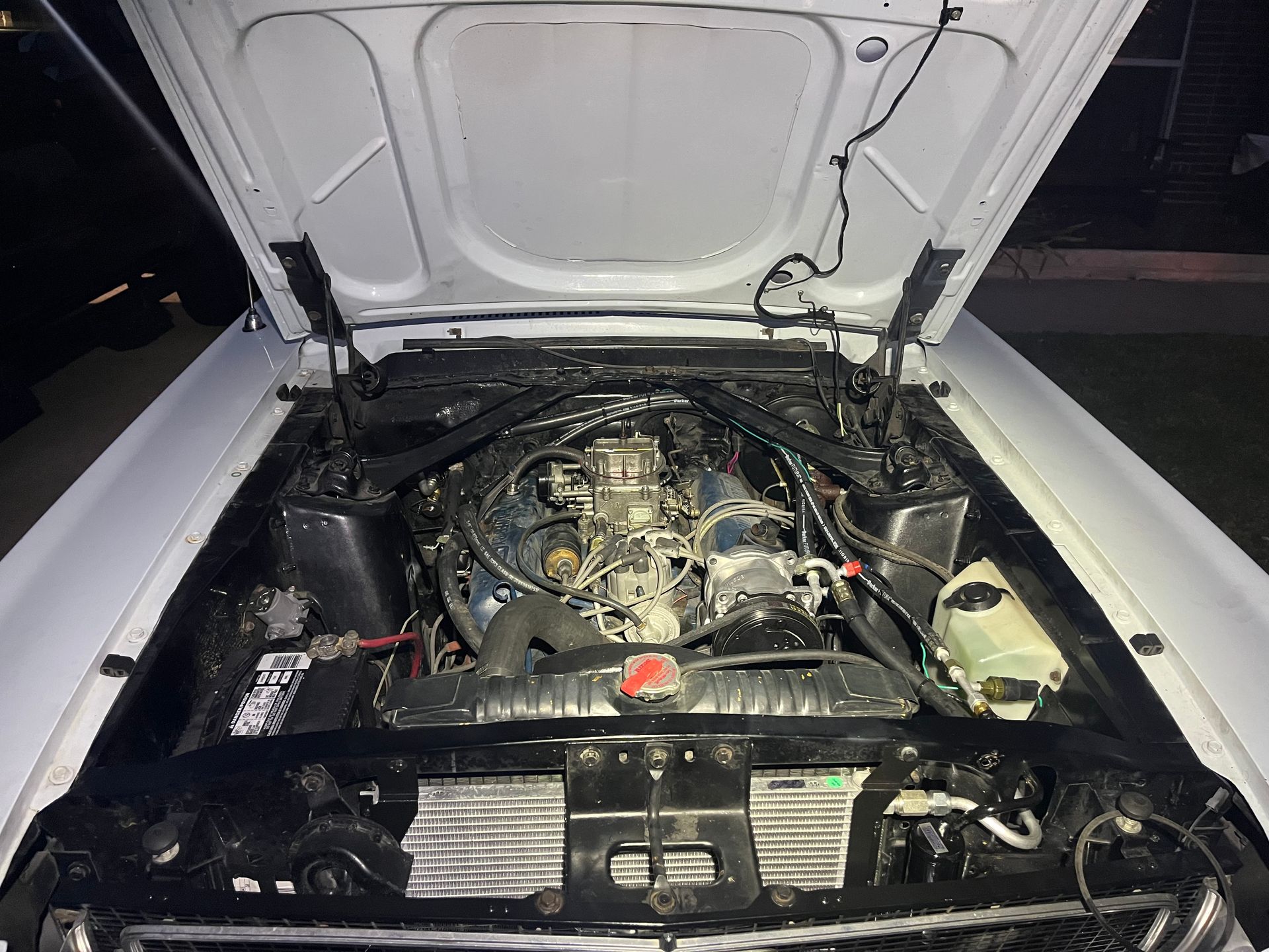 Open car hood showing exposed engine bay with visible wiring and components