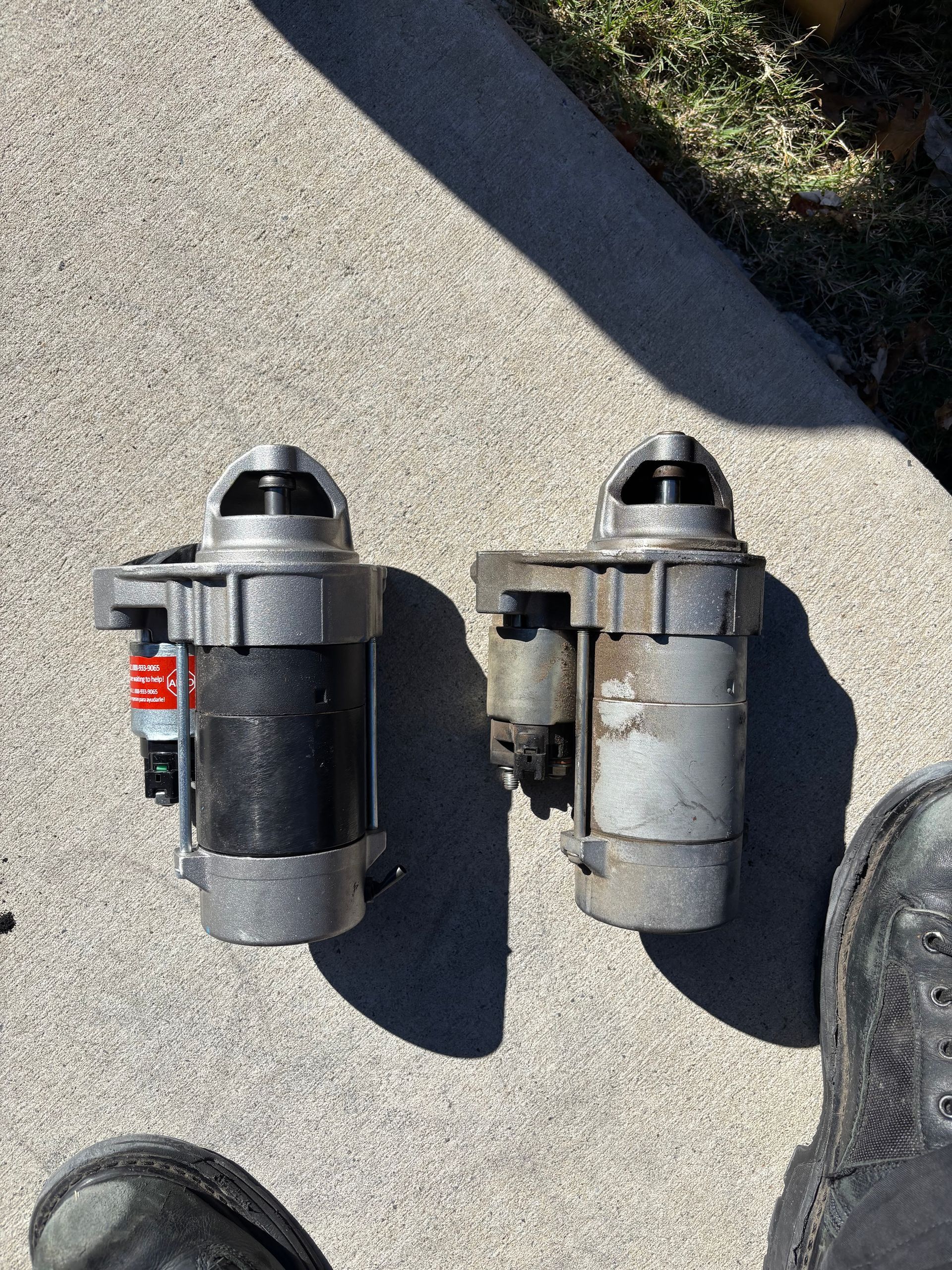 Two small black-and-silver mechanical devices lying on concrete beside a shoe and a shadow.