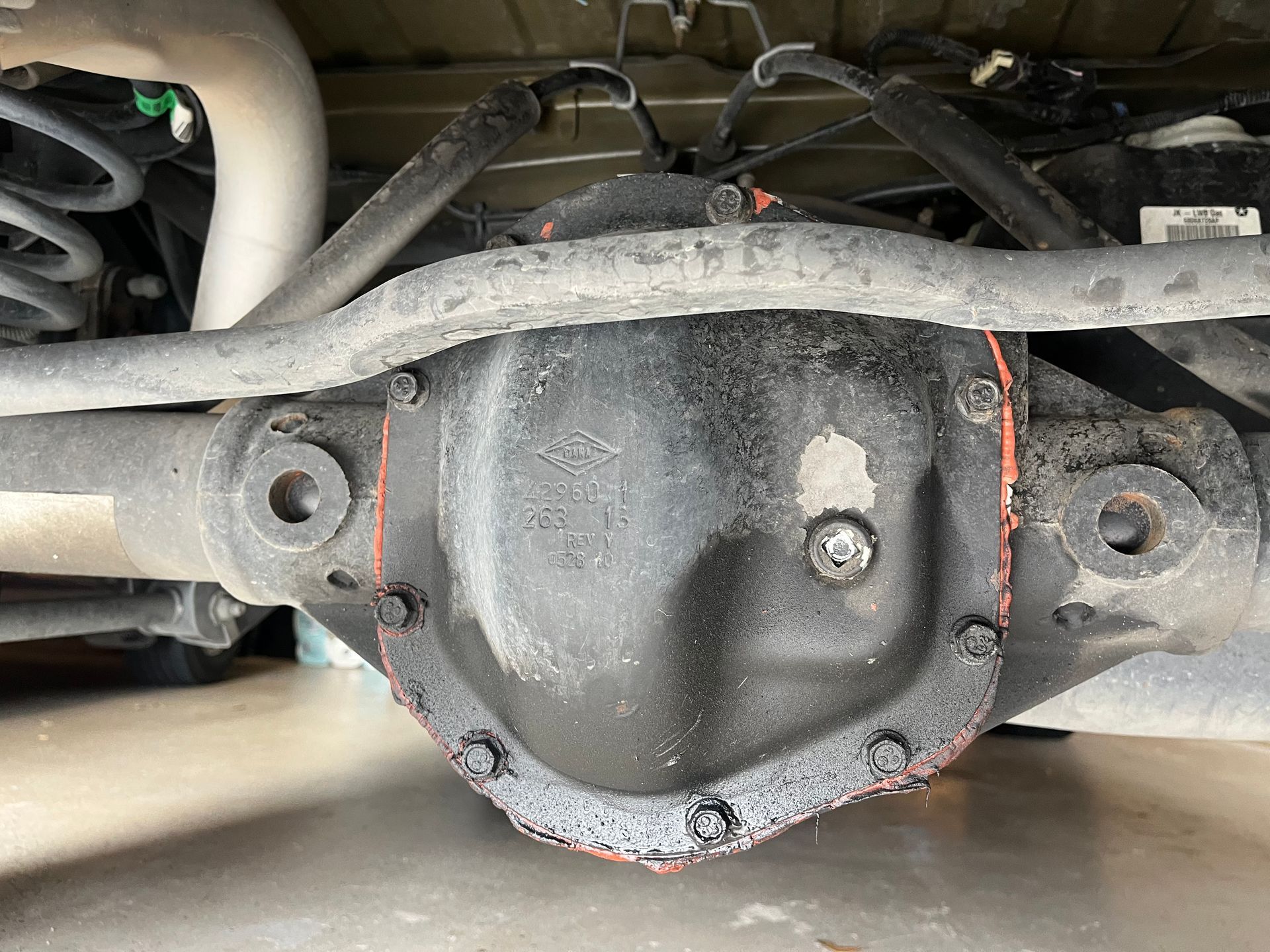 Rear axle differential housing under a vehicle, black metal cover with red gasket and bolts