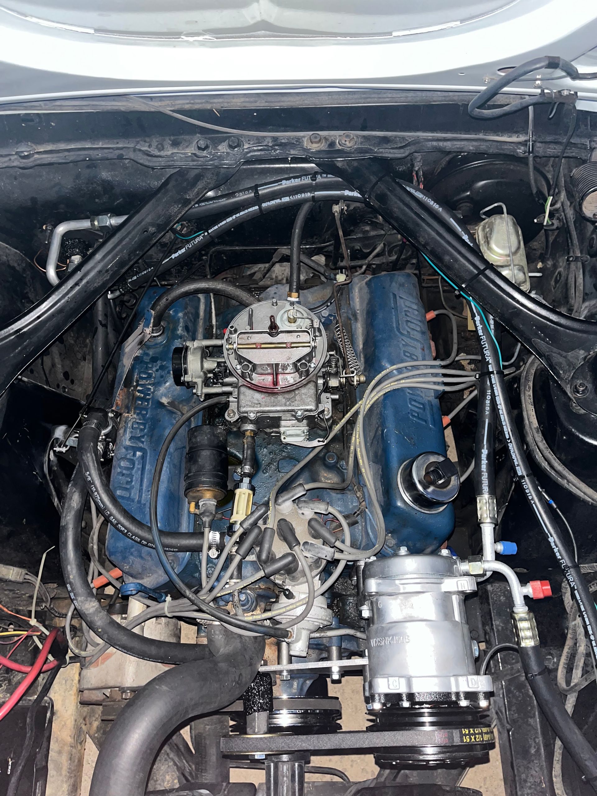 Car engine bay with blue engine block, black hoses, and a silver turbocharger assembly.